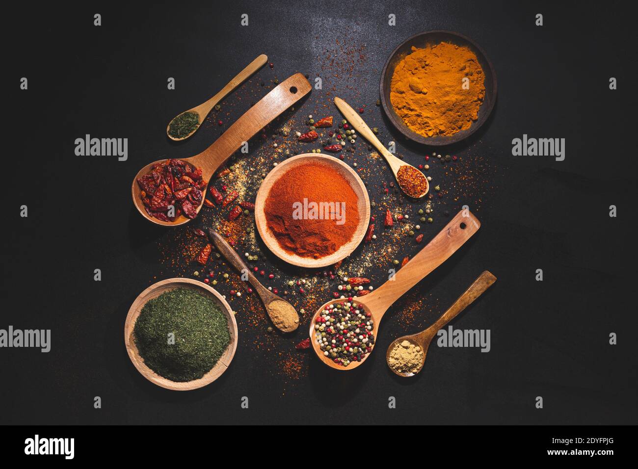 composizione con varietà di spezie ed erbe su sfondo nero vista dall'alto. Cucina ingredienti e condimenti concetto. Foto Stock