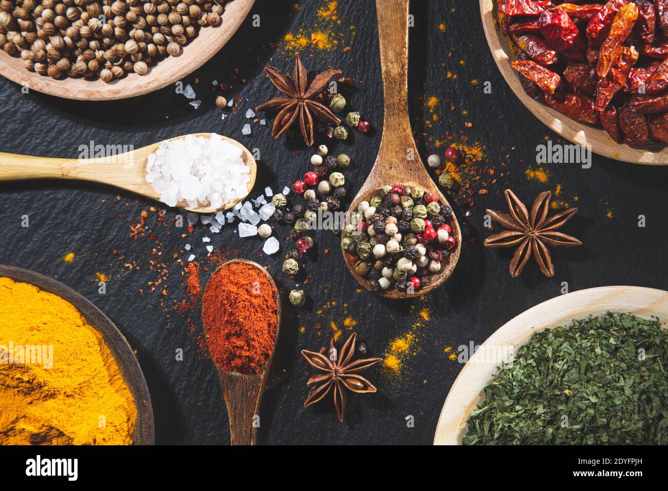 sfondo con varietà di spezie ed erbe su sfondo nero vista dall'alto. Cucina ingredienti e condimenti concetto. Foto Stock