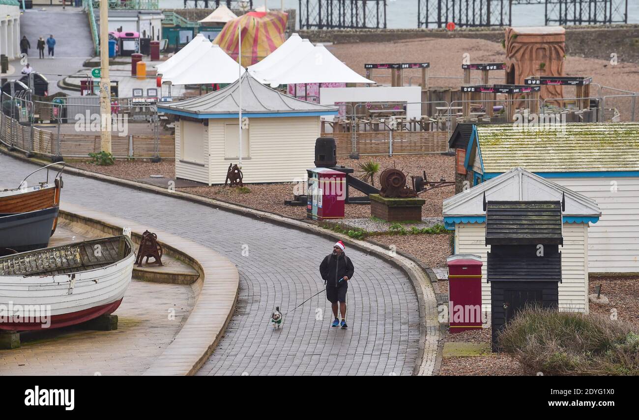 Brighton UK 26th December 2020 - UN camminatore di cane di giorno di Santo Stefano sul lungomare di Brighton durante il tempo noioso e arido lungo la costa meridionale, mentre Storm Bella si avvicina alla Gran Bretagna : Credit Simon Dack / Alamy Live News Foto Stock