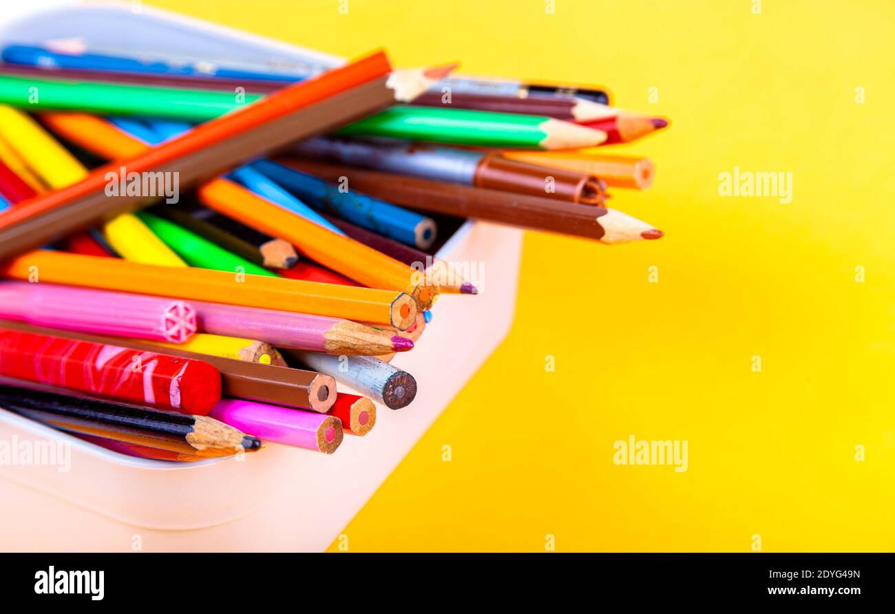 Un sacco di diversi pastelli di legno colorati, molti pastelli multicolore mescolati in un contenitore di scatola, closeup. Torna a scuola, attrezzature per disegno di classe artistica Foto Stock