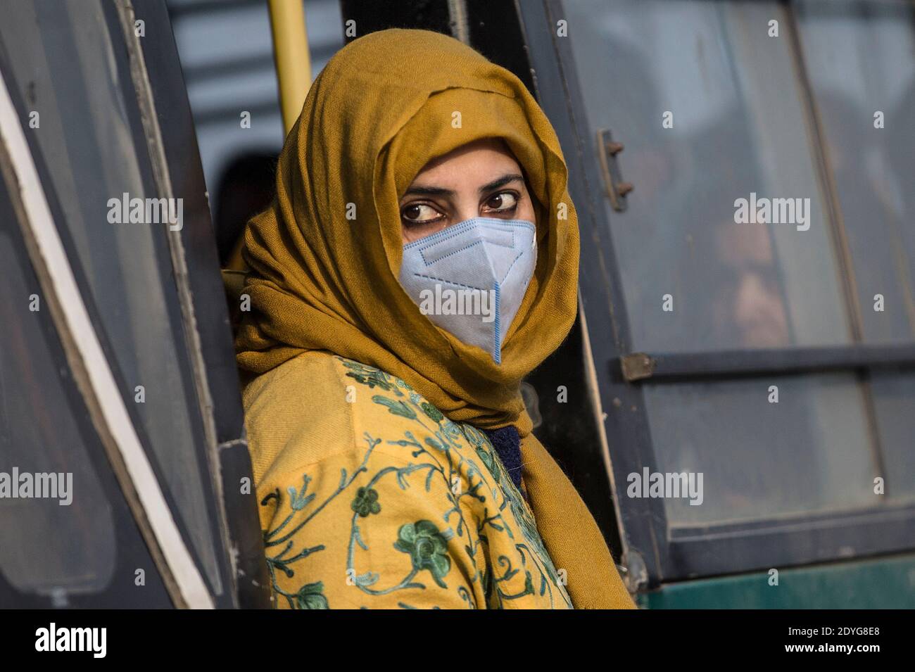 Srinagar, Kashmir controllato dall'India. 26 Dicembre 2020. Una donna che indossa una maschera facciale scende da un autobus nella città di Srinagar, la capitale estiva del Kashmir controllato dagli Indiani, il 26 dicembre 2020. Credit: Javed Dar/Xinhua/Alamy Live News Foto Stock