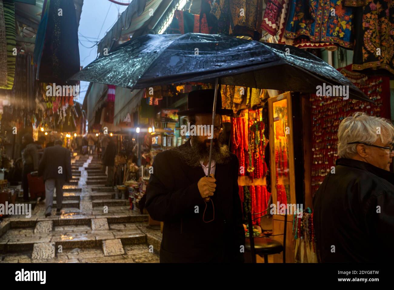 Gli ebrei ortodossi camminano lungo una strada nella città vecchia di Gerusalemme durante una pioggia, Israele Foto Stock