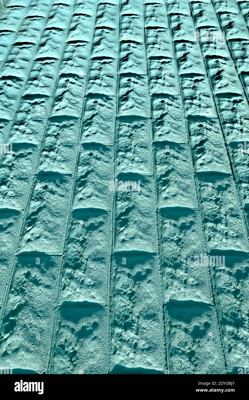La parete in pietra turchese testurizzata forma un disegno geometrico astratto di sfondo Foto Stock