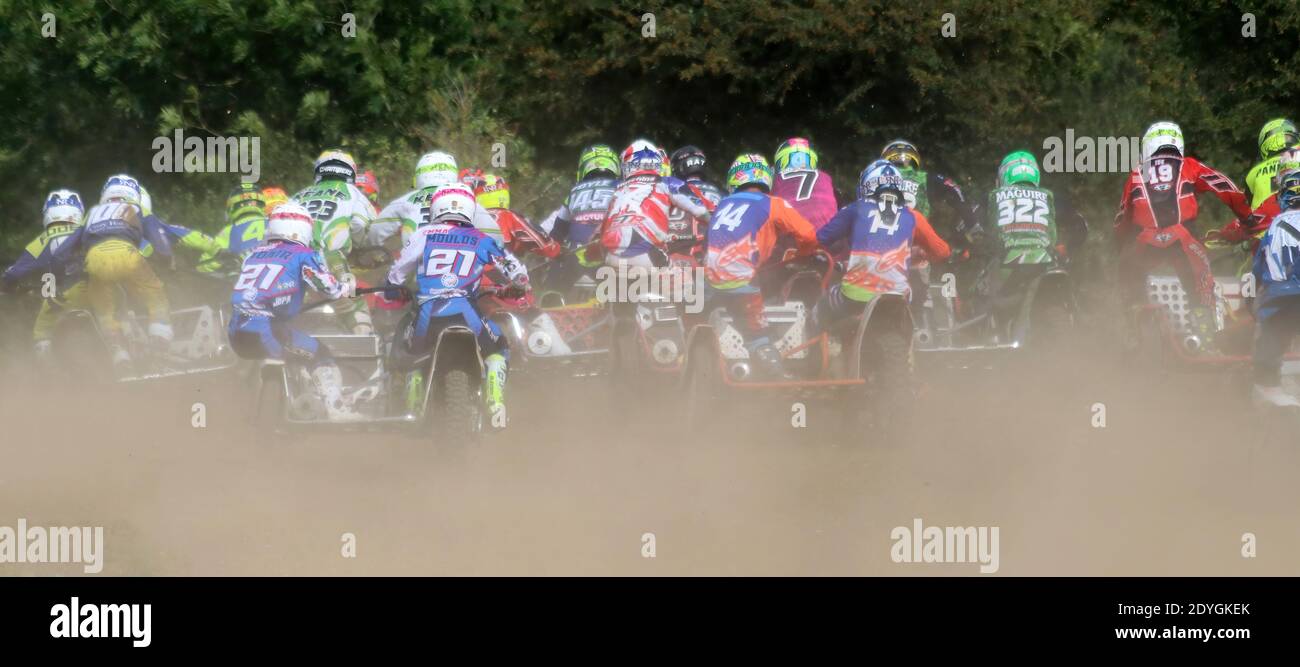 grande gruppo di abiti da moto-cross alla stella di una gara con polvere e sporcizia che volano ovunque Foto Stock