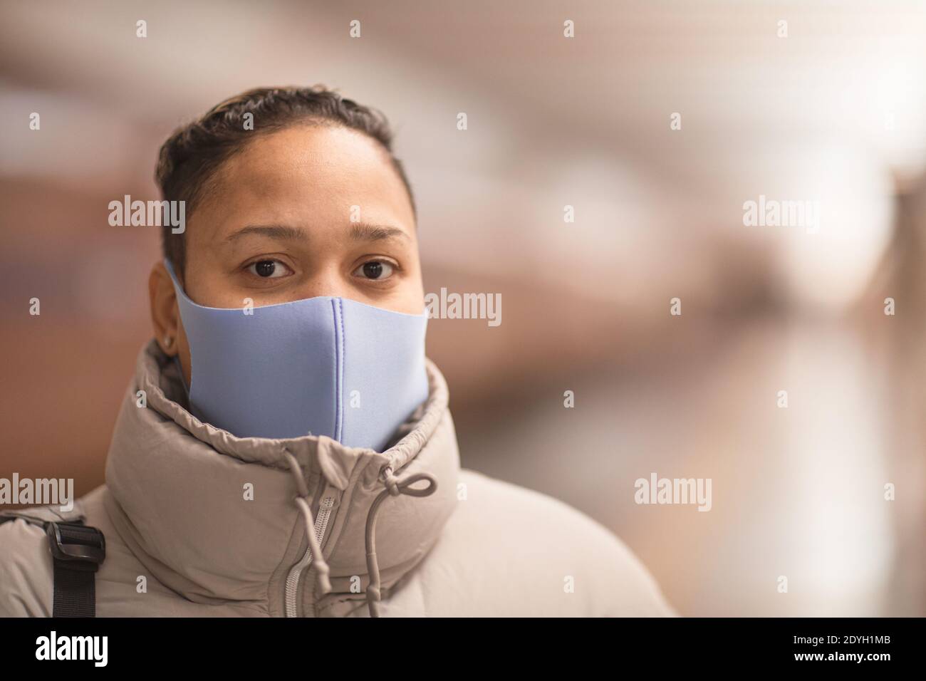Ritratto di giovane donna che indossa una maschera protettiva guardando la macchina fotografica Foto Stock