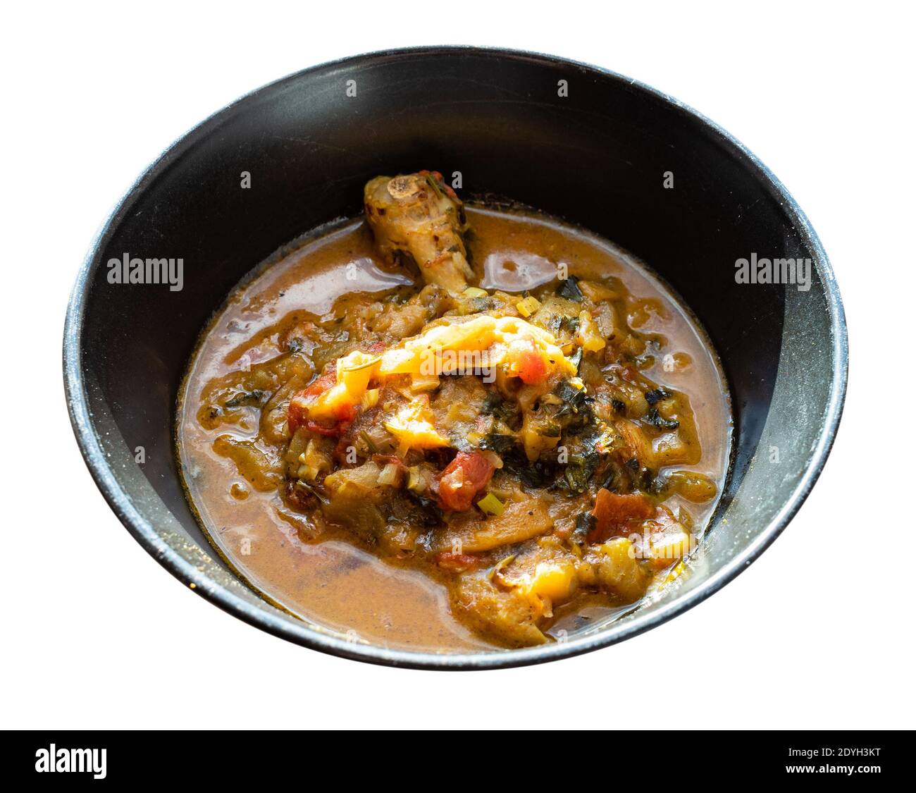 Chakhokhbili (piatto tradizionale georgiano di carne di pollo stufata, pomodoro, melanzane ed erbe fresche) in ciotola nera tagliata su sfondo bianco Foto Stock