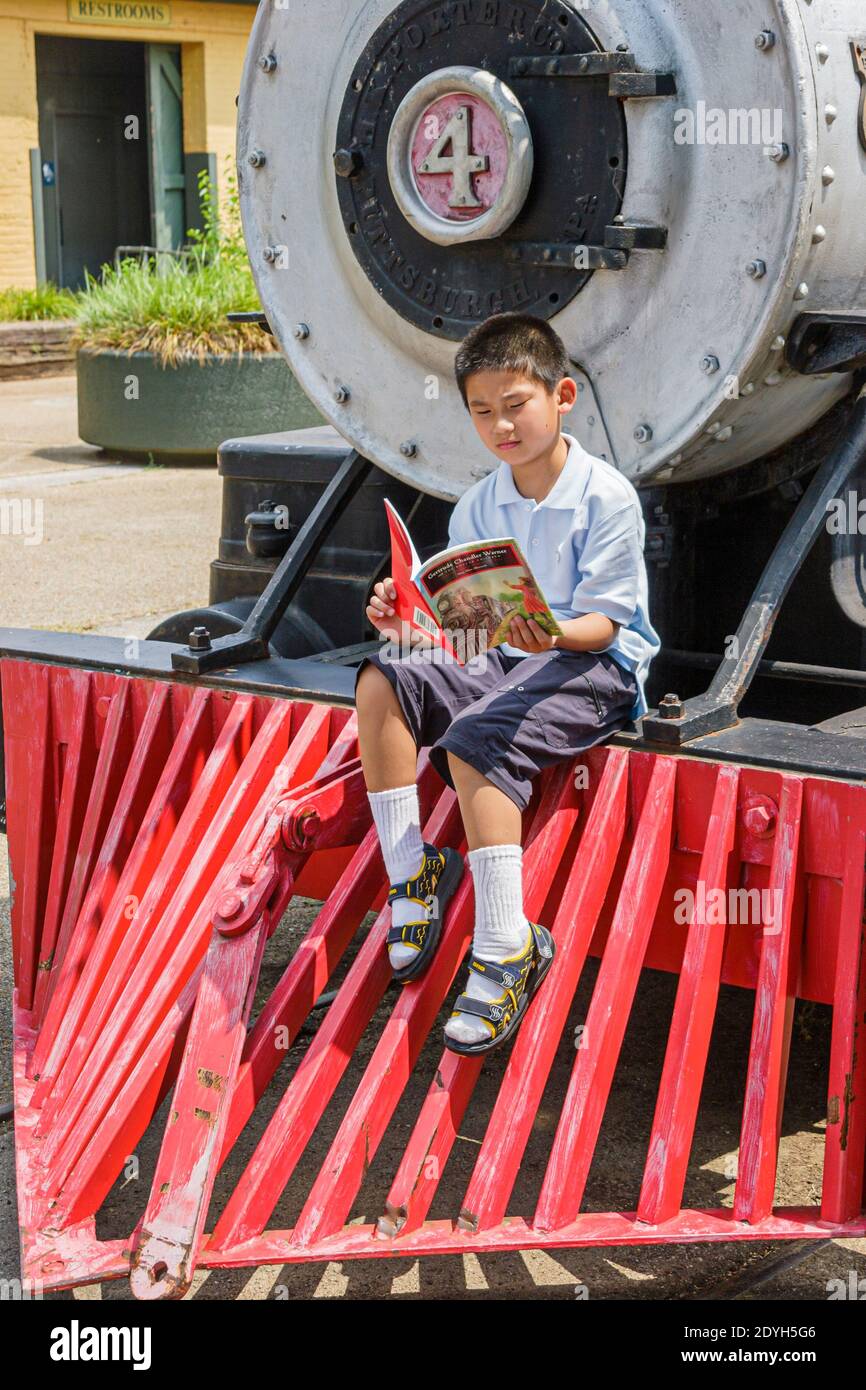 Huntsville, Alabama, museo deposito costruito 1860 stazione ferroviaria, ragazzo asiatico seduto lettura locomotiva cowcatcher, Foto Stock