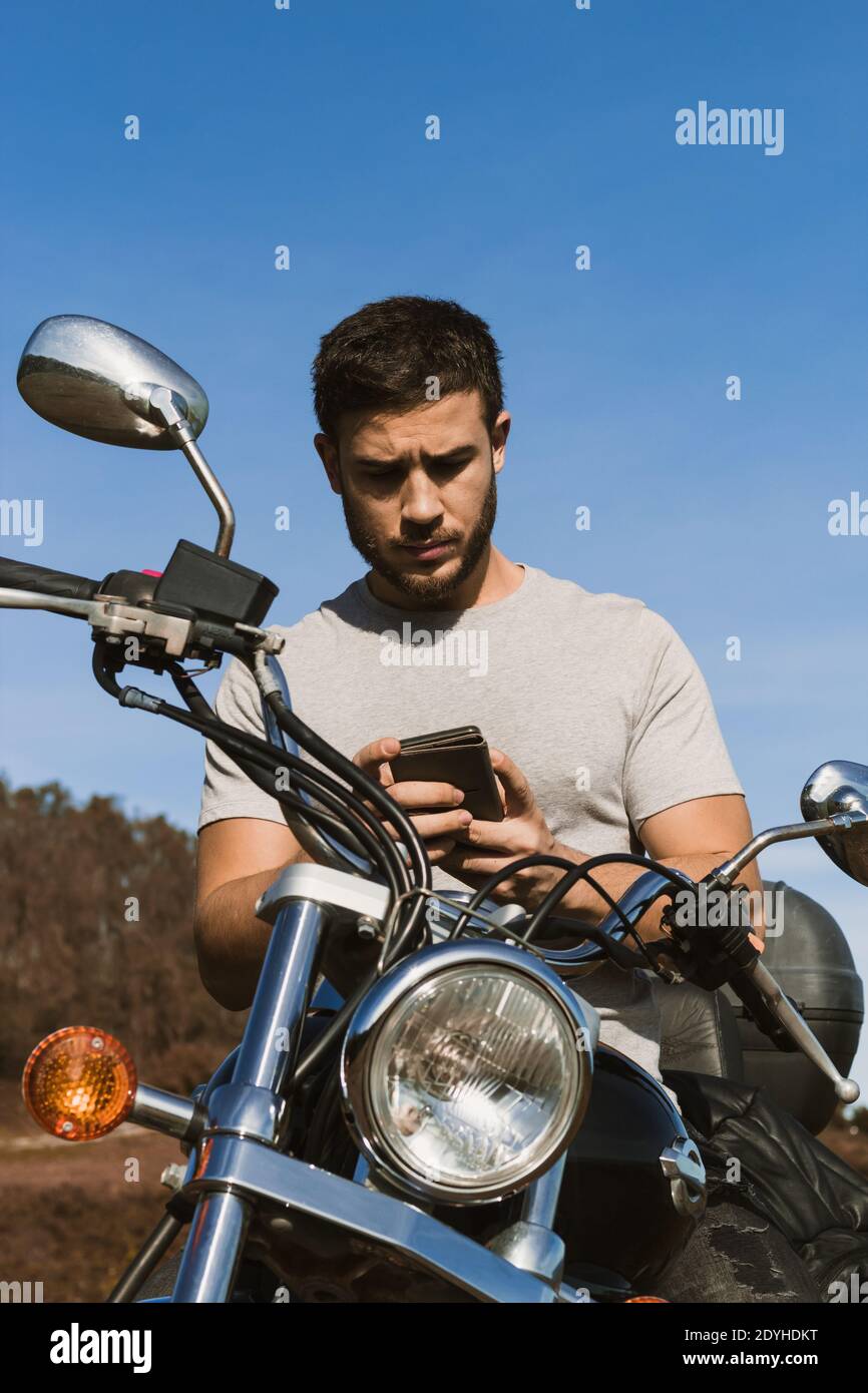 Motociclista che guarda il cellulare durante un percorso Foto Stock