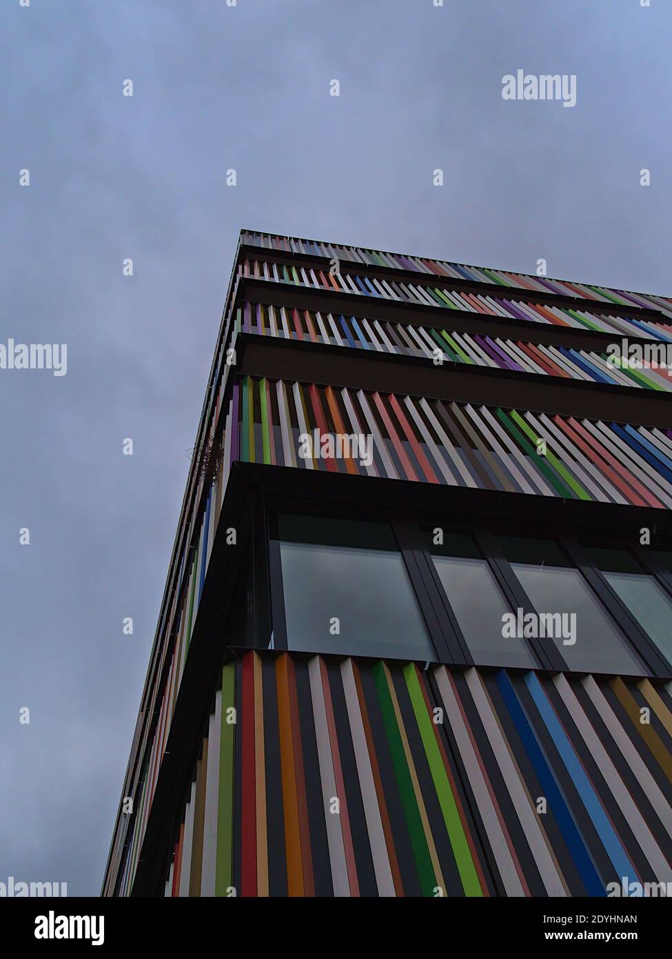 Vista ad angolo basso di un moderno edificio residenziale con balconata multicolore e finestre sulla facciata in un giorno nuvoloso. Foto Stock