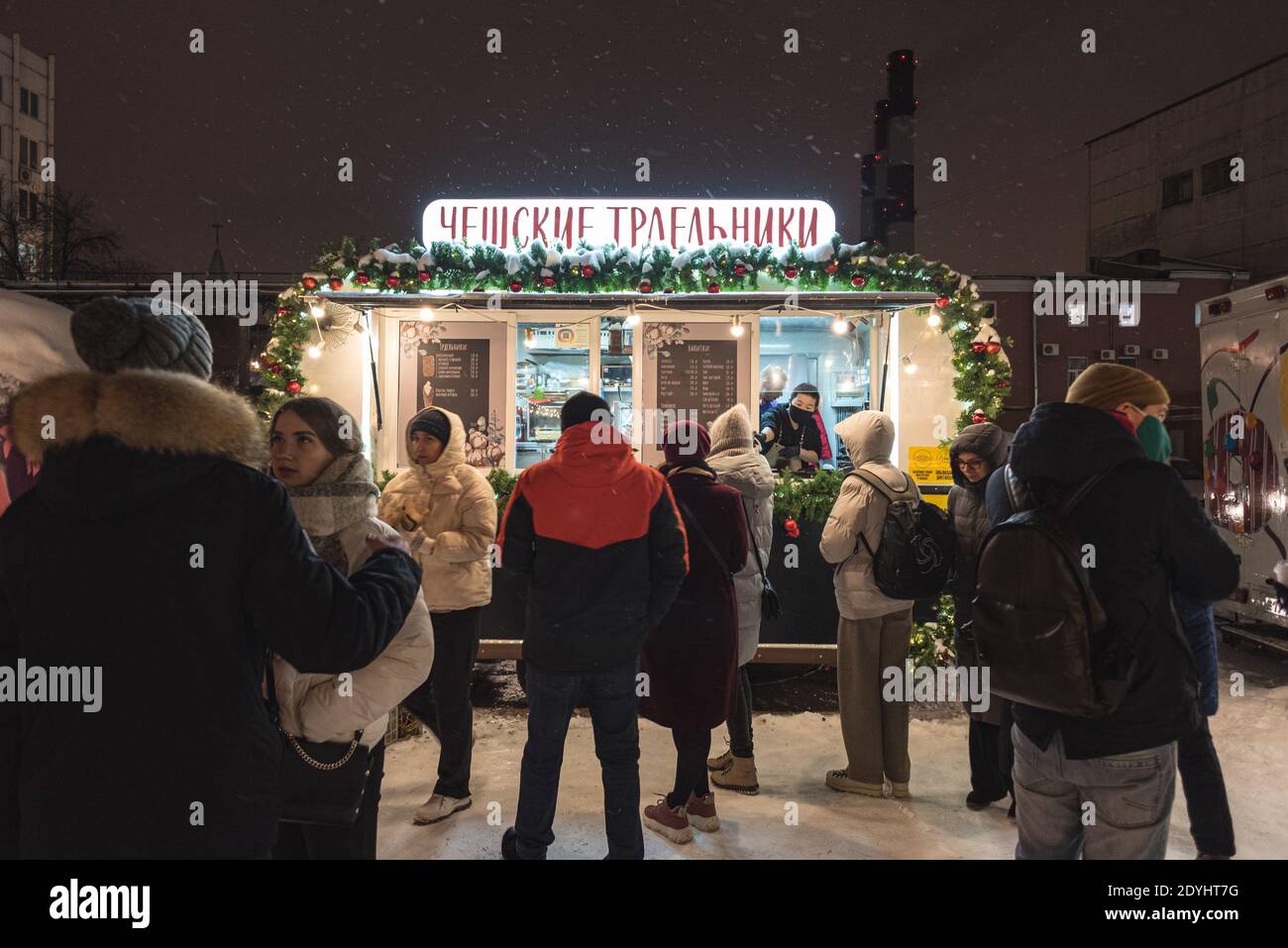 San Pietroburgo, Russia - 26 dicembre 2020: I giovani si levano in fila per la pasticceria ceca (trdelniks) in un negozio di strada di notte Sevkabel Port. Foto Stock