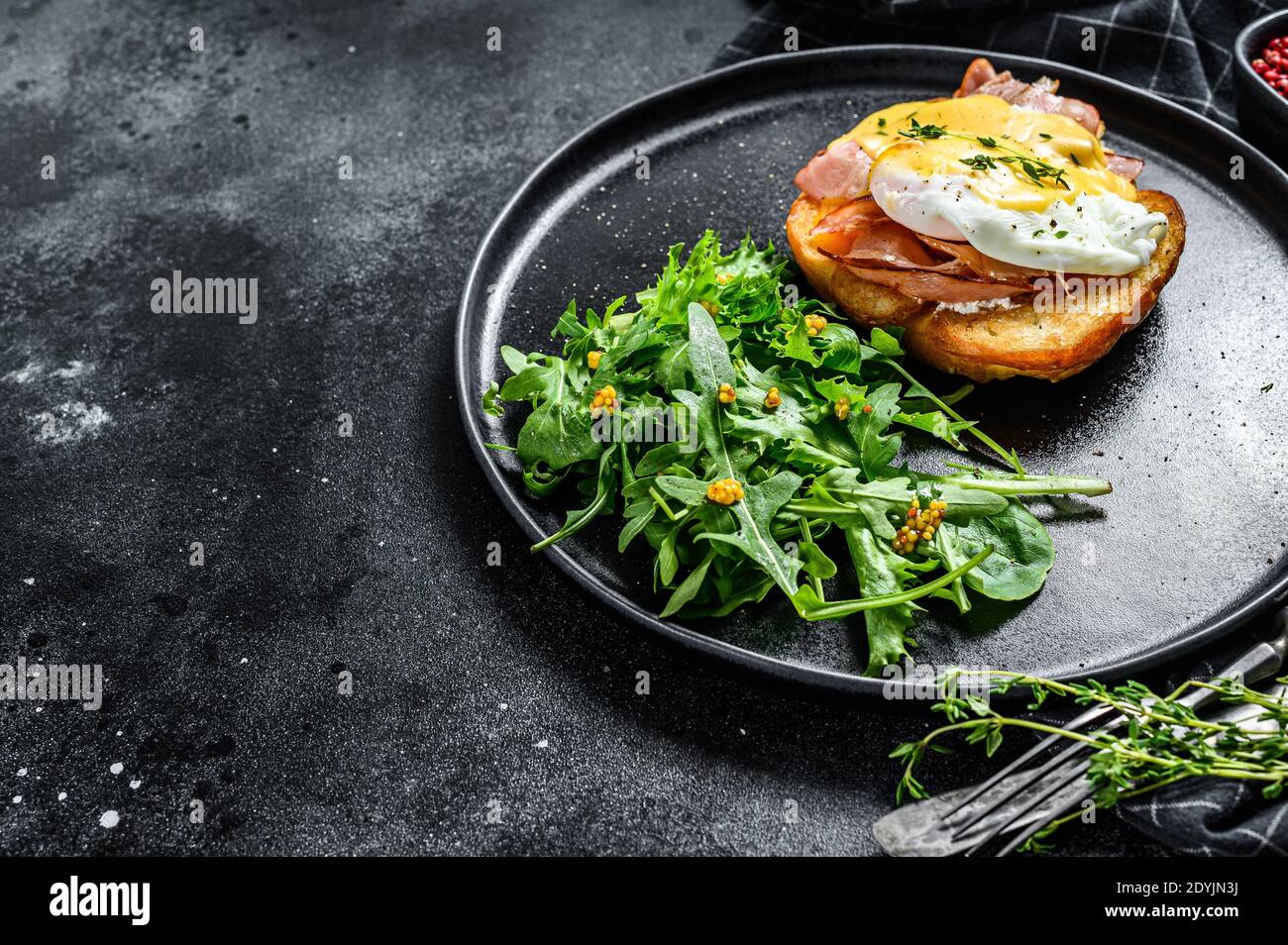 Prima colazione Burger con pancetta, uovo Benedetto, salsa hollandaise su brioche pann. Sfondo nero. Vista dall'alto. Spazio di copia Foto Stock