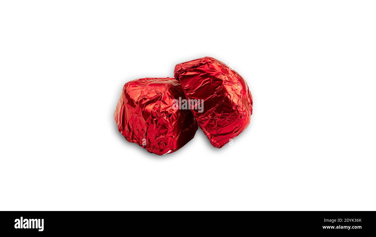 Dolce caramella a forma di cuore di cioccolato avvolto in papper di lamina rossa su sfondo bianco. Foto di alta qualità Foto Stock