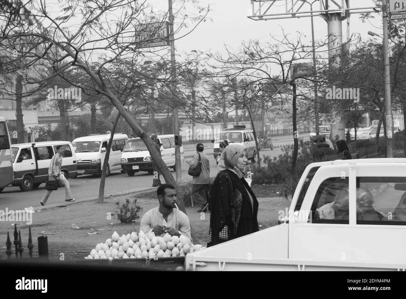Cairo Egitto : la strada con le automobili, un camion, egiziani a piedi e un uomo fumante che vende frutta Foto Stock