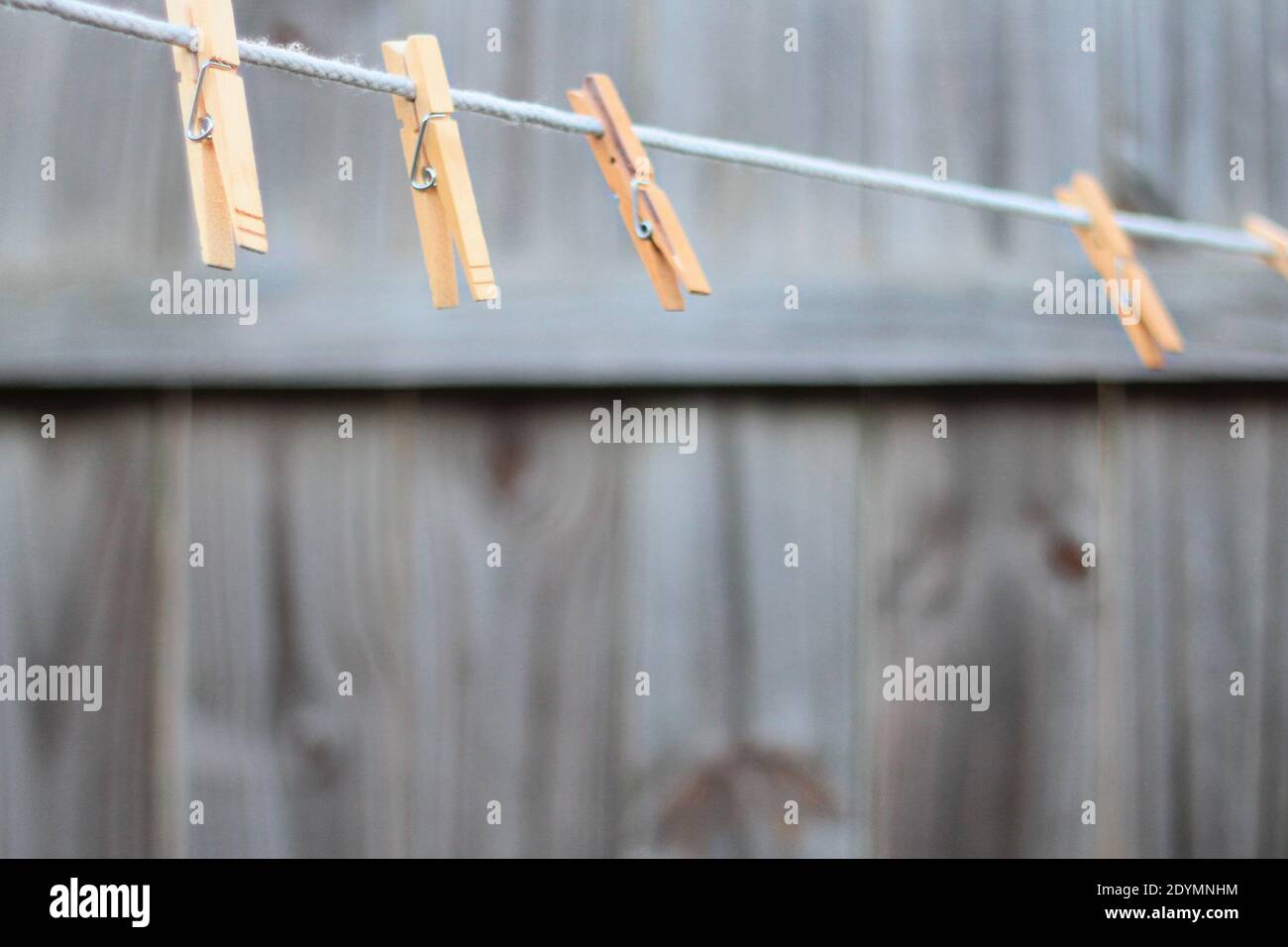 Uno stendibiancheria vuoto con stendibiancheria in legno pende in un cortile con recinzione in legno sullo sfondo. Foto Stock