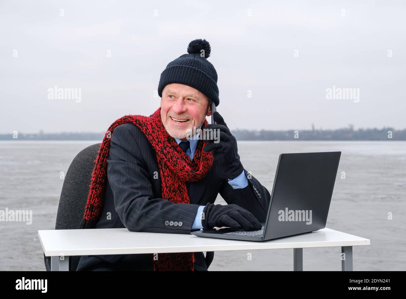 uomo d'affari anziano con la bearded grigia in tuta, sorridente mentre parla sullo smartphone Foto Stock