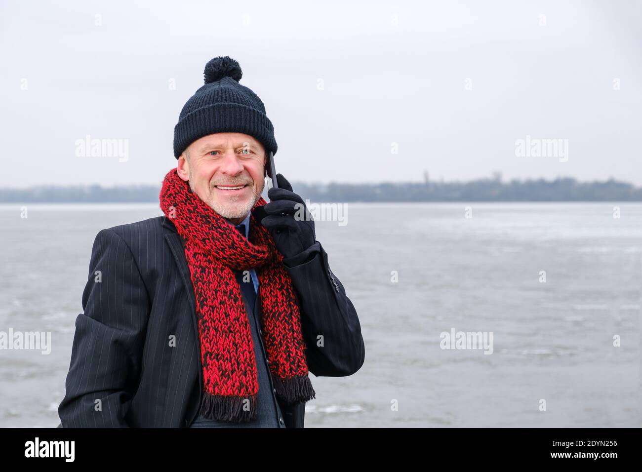 Ritratto di un anziano che parla sul telefono cellulare sul lago ghiacciato. Foto Stock