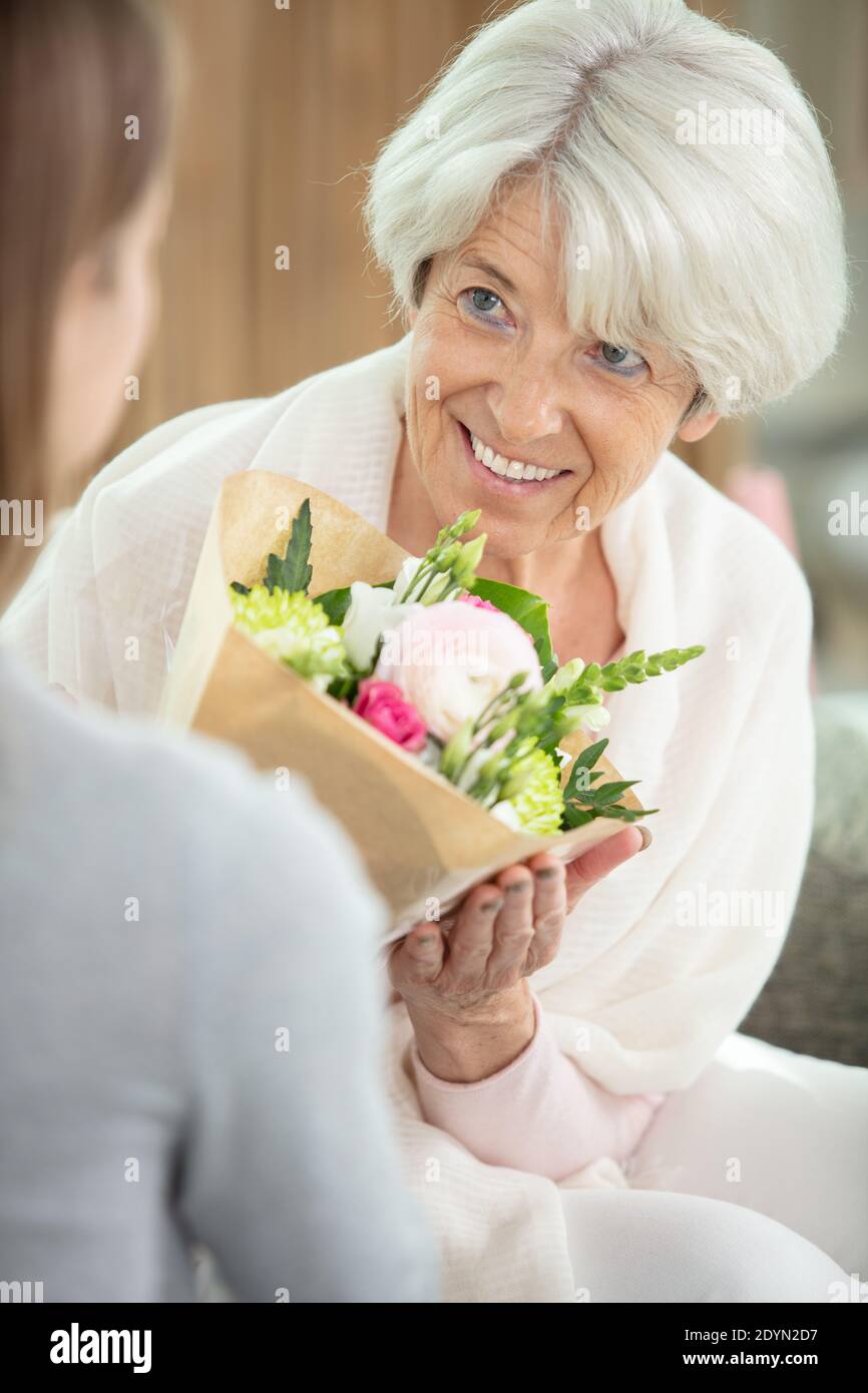 la donna sta dando fiori alla madre matura Foto Stock