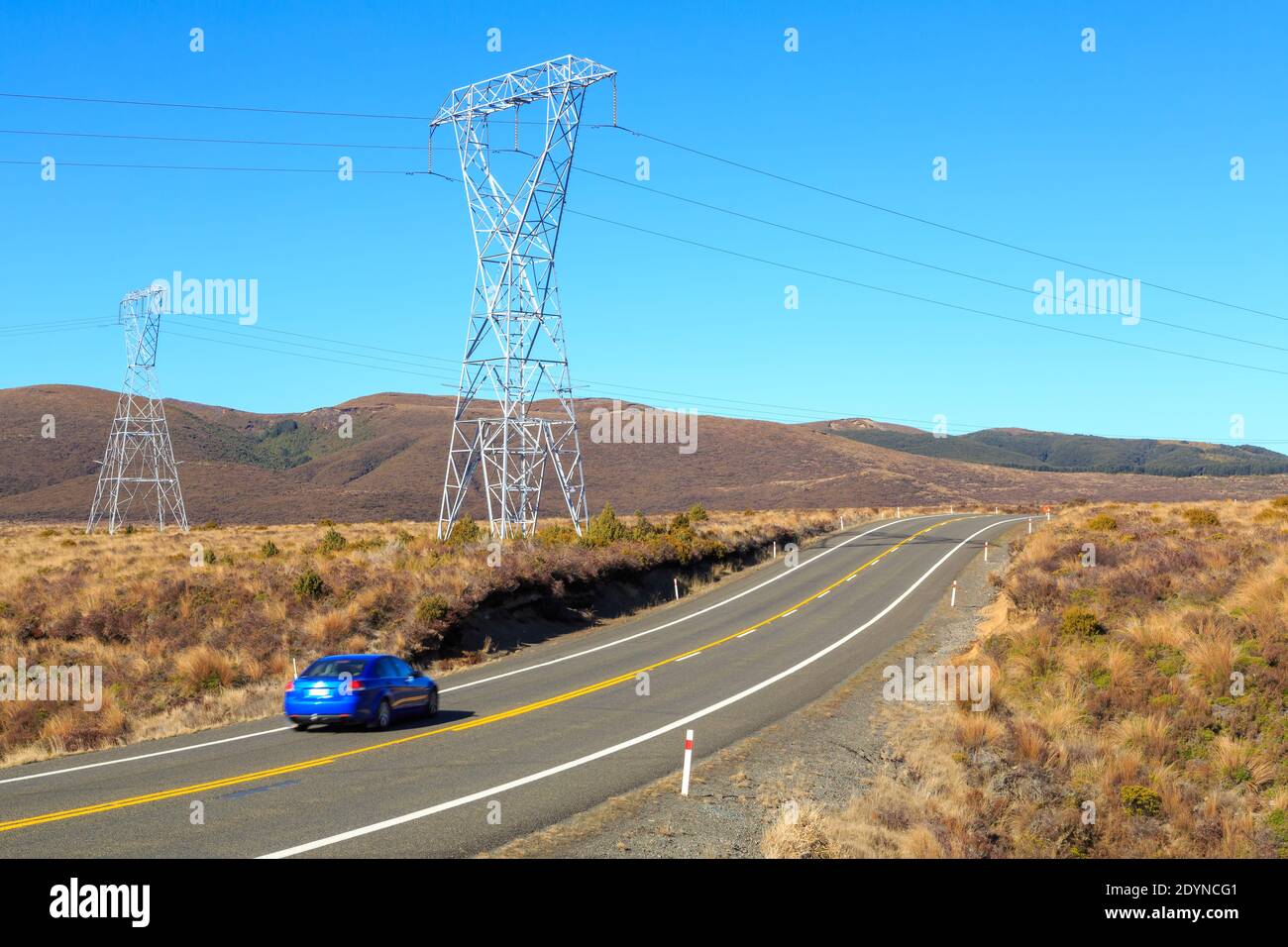 State Highway 1 ('The Desert Road') passando attraverso le praterie del deserto di Rangipo, Nuova Zelanda. Grandi tralicci di potenza corrono lungo la strada Foto Stock