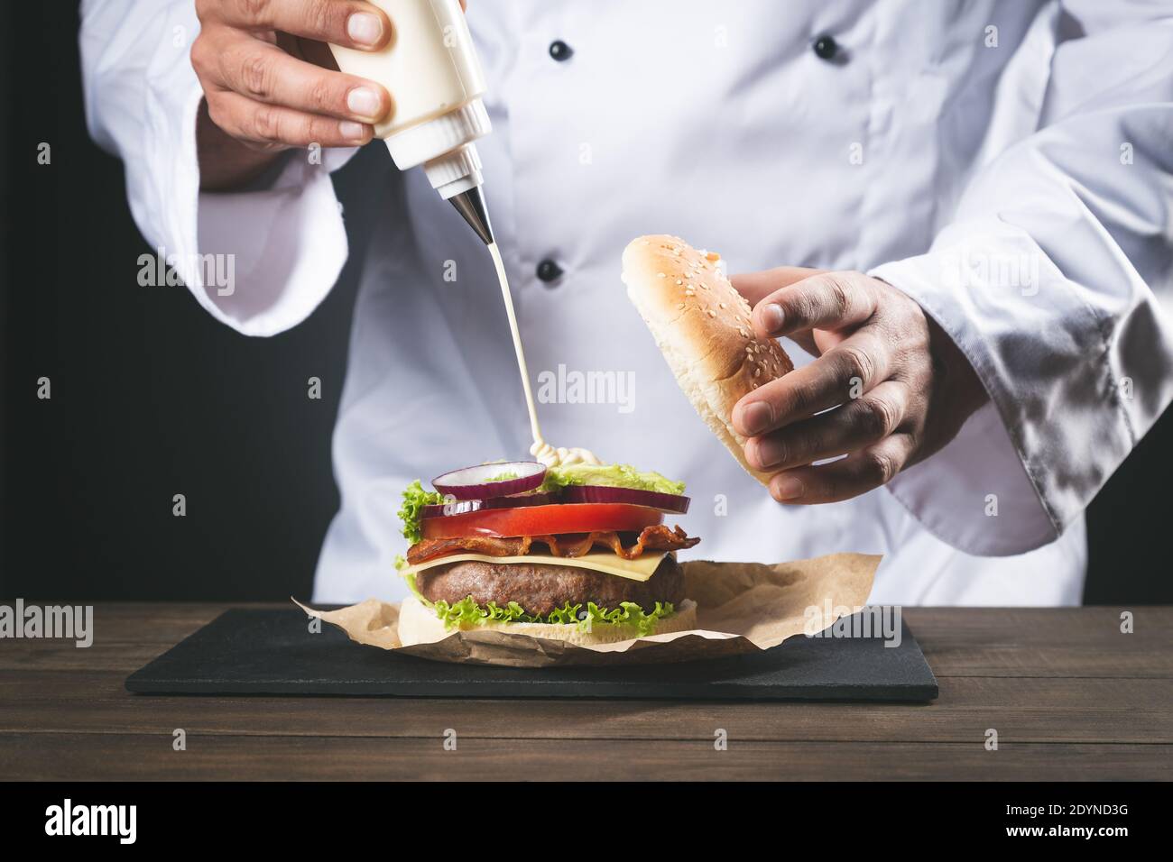 Chef prepara hamburger su tavolo di legno. Foto Stock