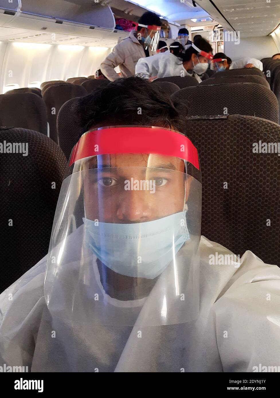 Un passeggero di volo indiano seduto all'interno di un aereo mentre indossa maschera facciale fornita dalle compagnie aeree Foto Stock