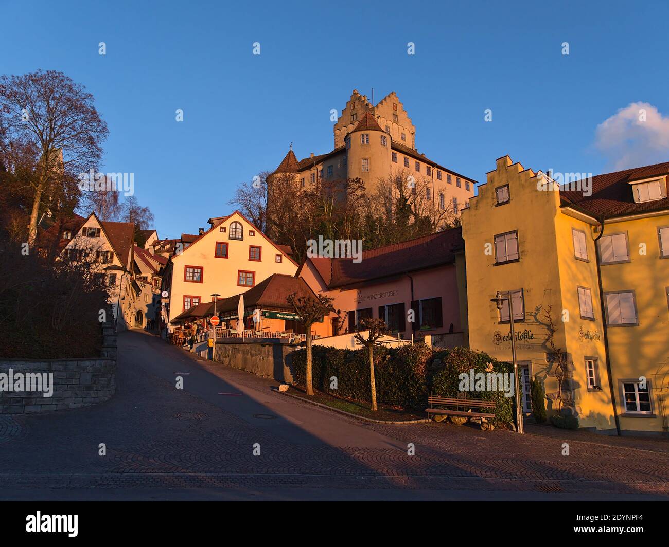 Bella vista del centro storico con vuota strada acciottolata, vecchi edifici e il simbolo castello di Meersburg sul pendio in luce notturna in inverno. Foto Stock