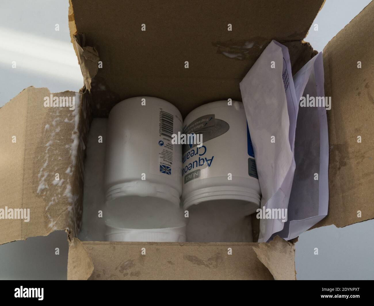 Due vaschette di crema acquosa ordinate online ricevute in pacchi le parti superiori si sono staccate e il contenuto si è versato nella scatola di cartone Foto Stock