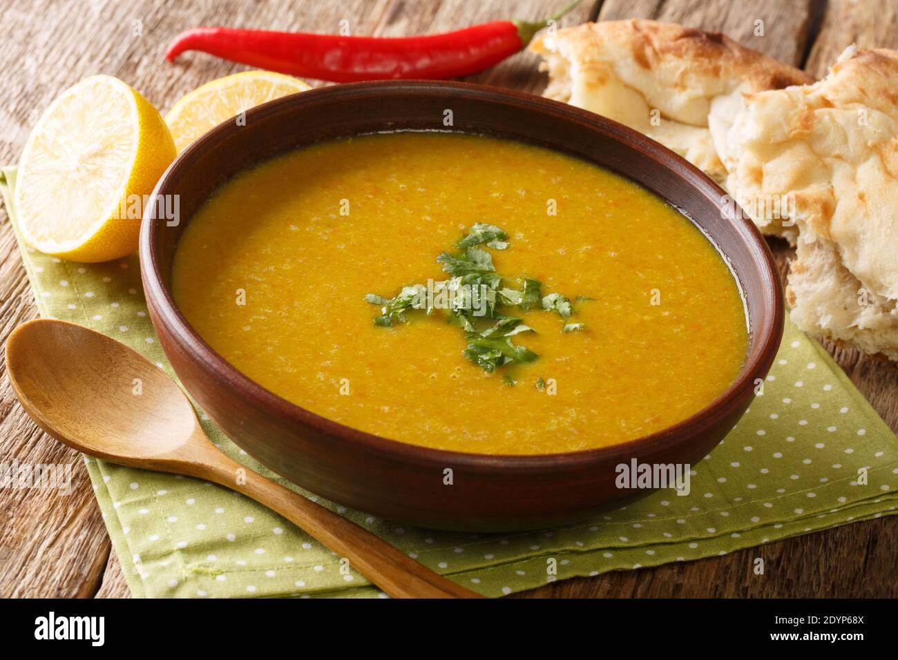 Zuppa di purea di lenticchie rosse servita con pane e primo piano di limone in una ciotola sul tavolo. Orizzontale Foto Stock