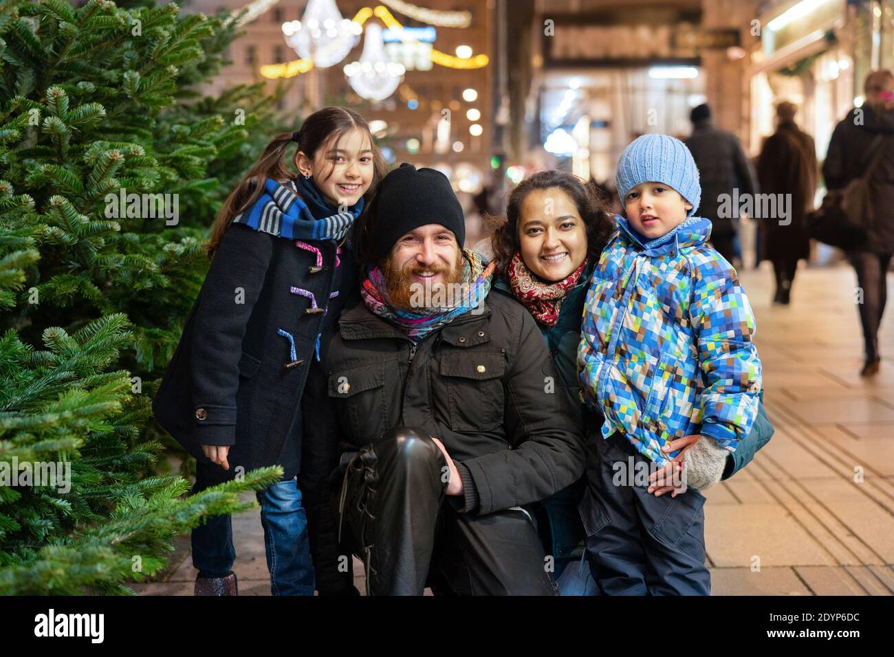 Felice multinazionale famiglia all'aperto in un centro città a Natale Foto Stock