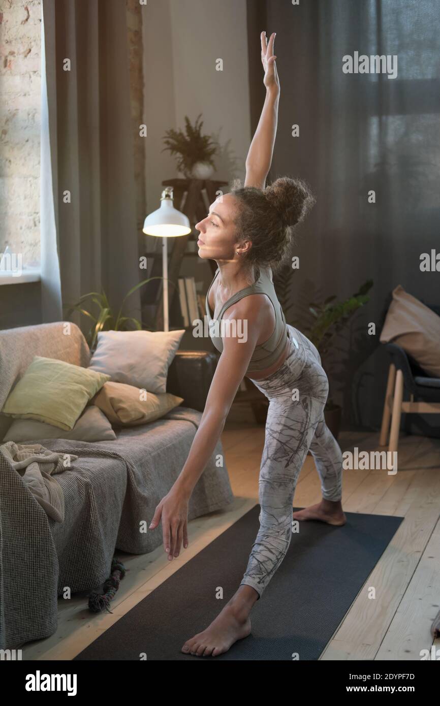 Giovane donna sana che si allunga durante l'allenamento sportivo in camera Foto Stock