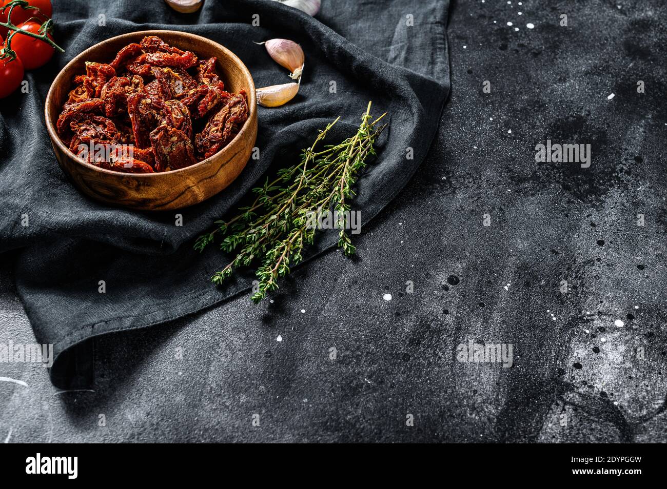 Pomodori secchi con aglio, spezie ed erbe. Ricetta per cucinare con gli ingredienti. Nero, sfondo scuro. Vista dall'alto. Spazio di copia. Foto Stock
