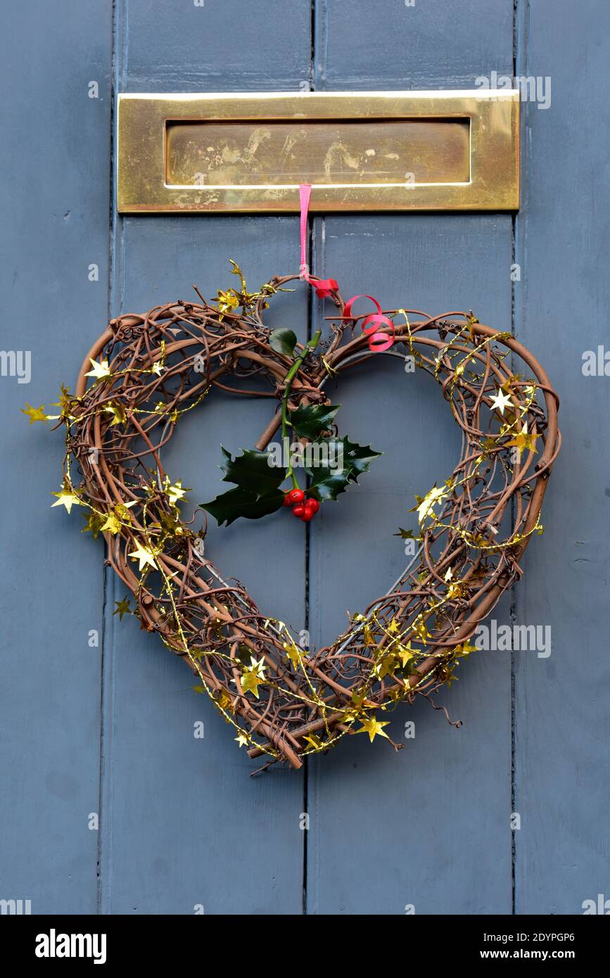 La decorazione a forma di cuore di Natale è appesa al nastro rosso festivo su una porta di legno nella pittoresca città di Ludlow, Shropshire, Inghilterra, Regno Unito. Foto Stock