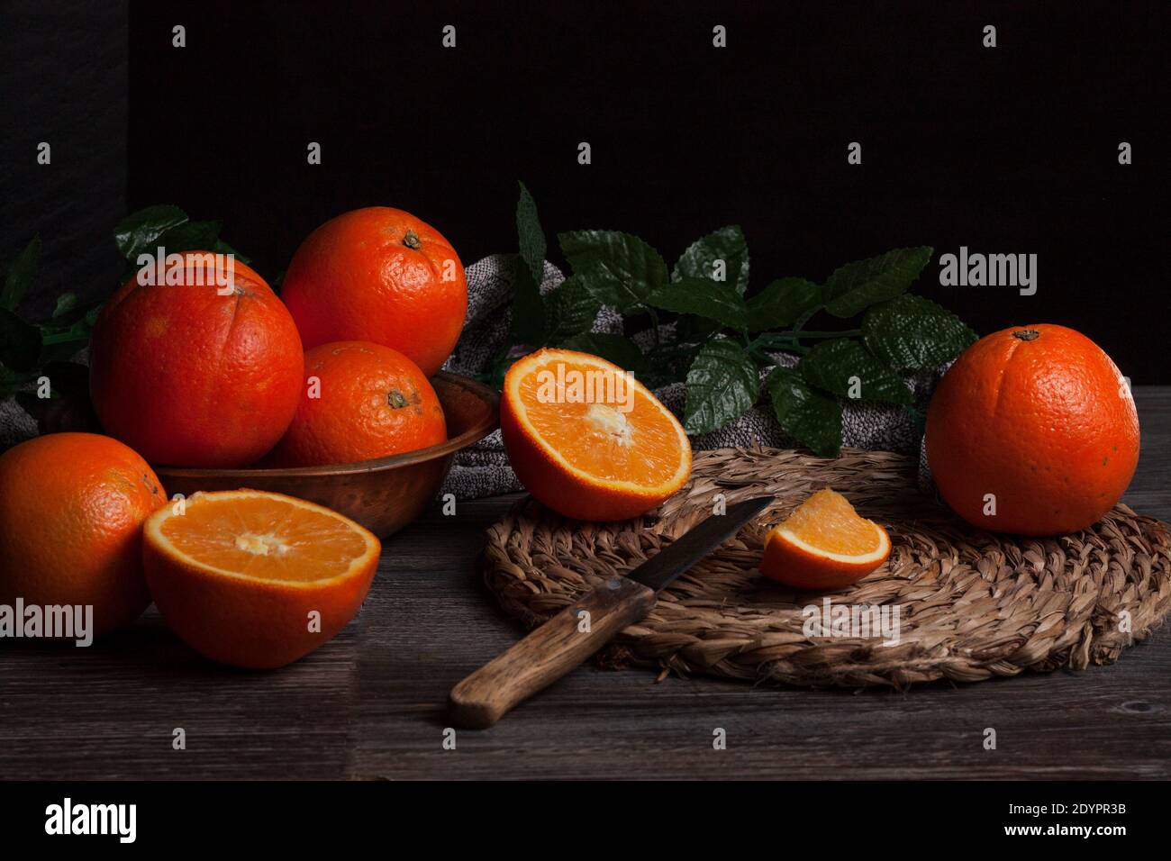 Ancora vita di arance su un tavolo tradizionale con un coltello e un esparto placemat. Foto Stock