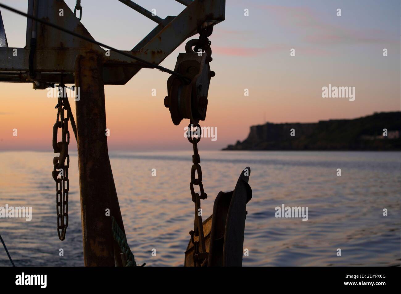 La poppa di un peschereccio costiero al tramonto che mostra blocchi, porta a strascico e catene. Canale Inglese Inghilterra Regno Unito GB Foto Stock