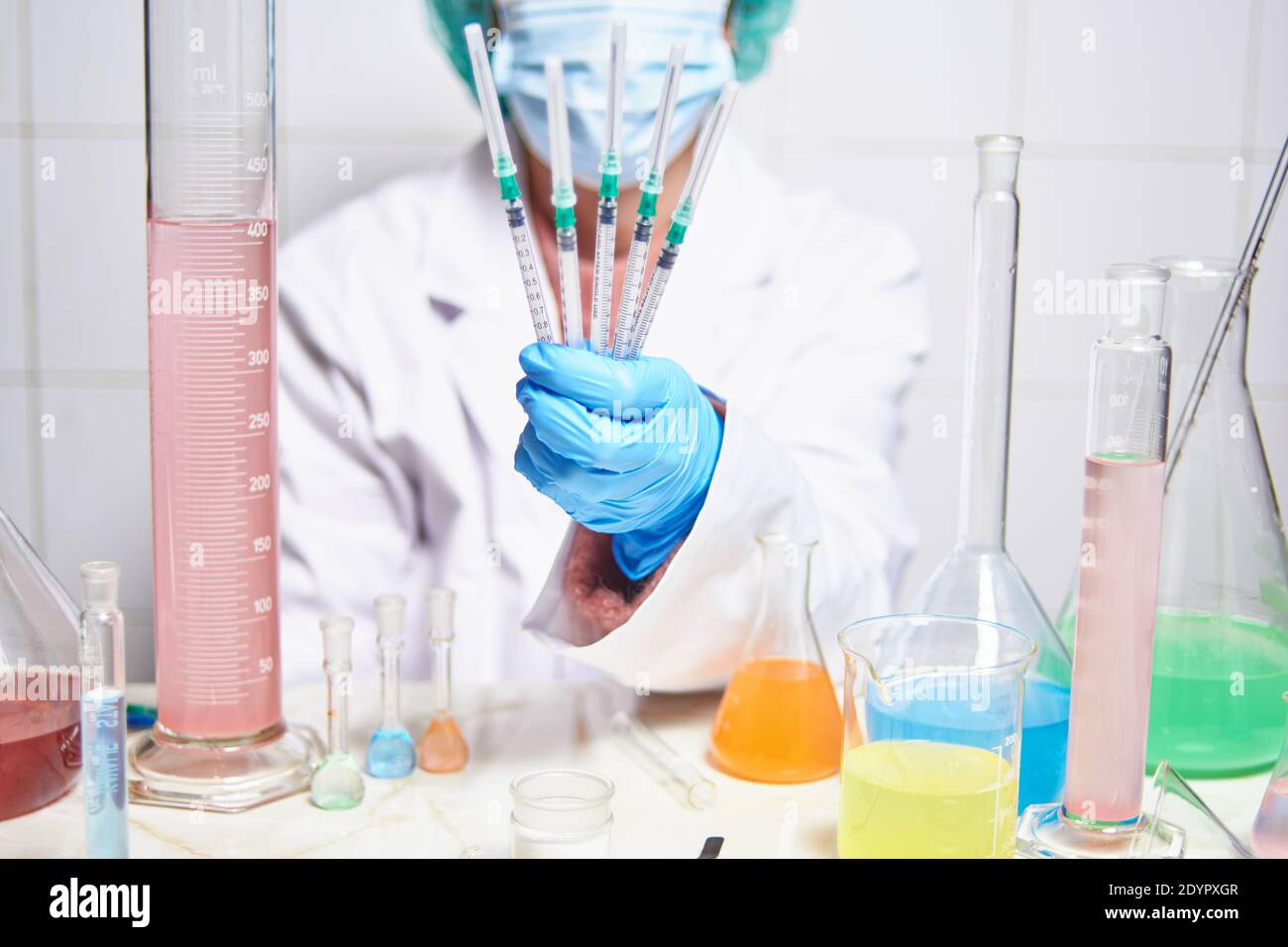 scienziato femminile con maschera facciale lavorando in laboratorio tenendo in mano diversi vaccini per il nuovo virus del coronavirus, covid19 Foto Stock