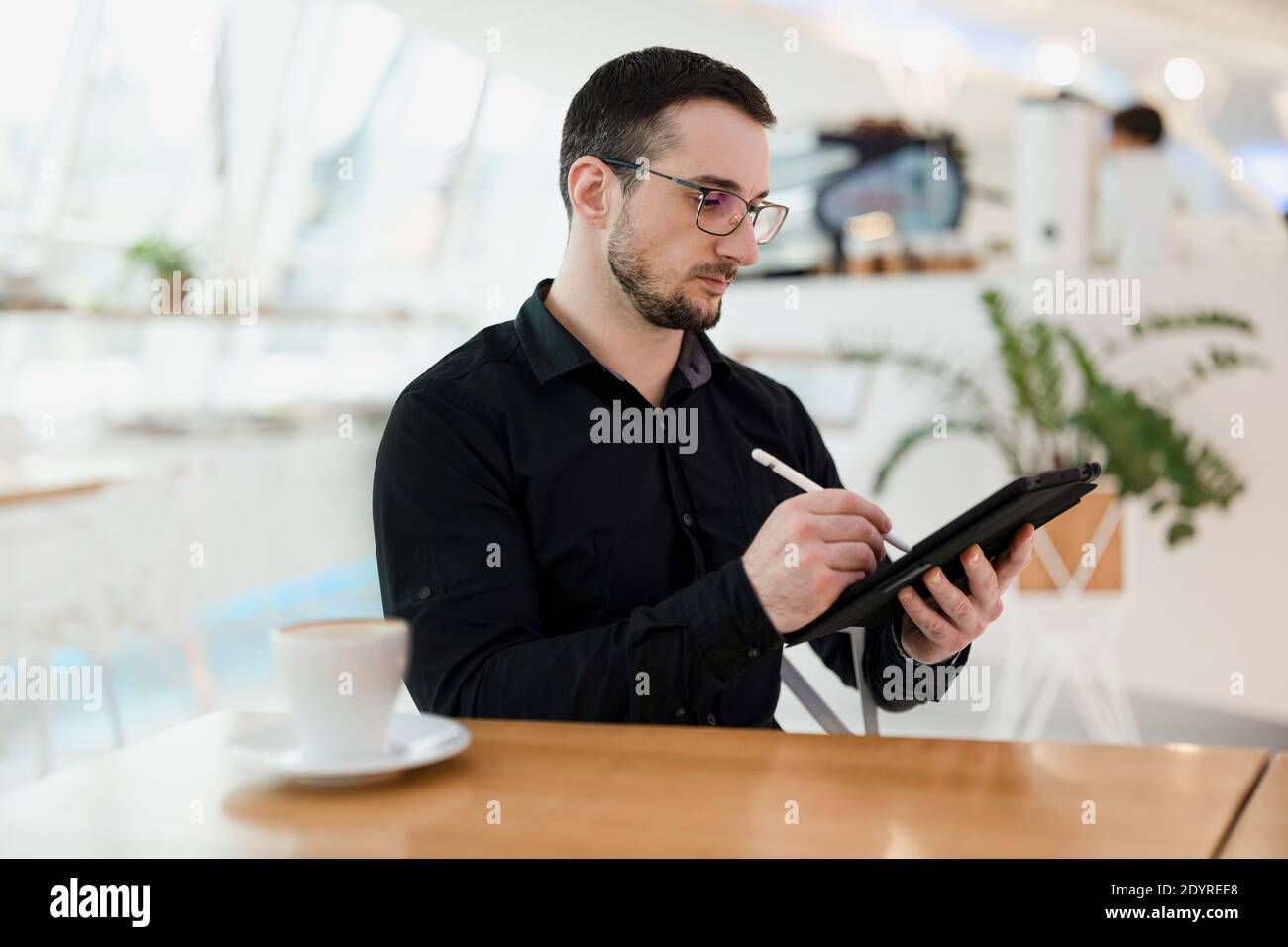 Web designer maschile o artista che disegnano sul suo tablet. Concetto di grafica digitale. Giovane uomo concentrato con barba e occhiali utilizzando il suo gadget Foto Stock