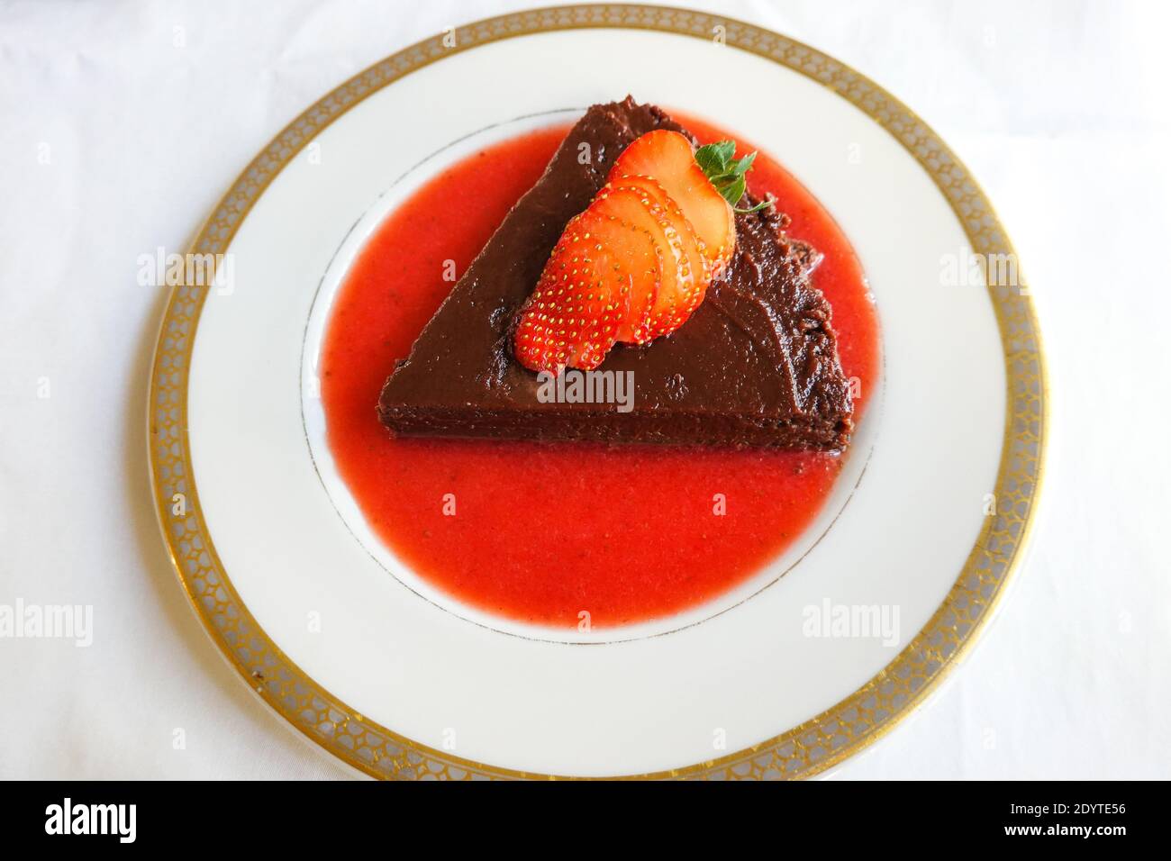 Terrina di cioccolato fatta in casa con una salsa di fragole fresca guarnita con una fragola fresca tagliata a fette Foto Stock