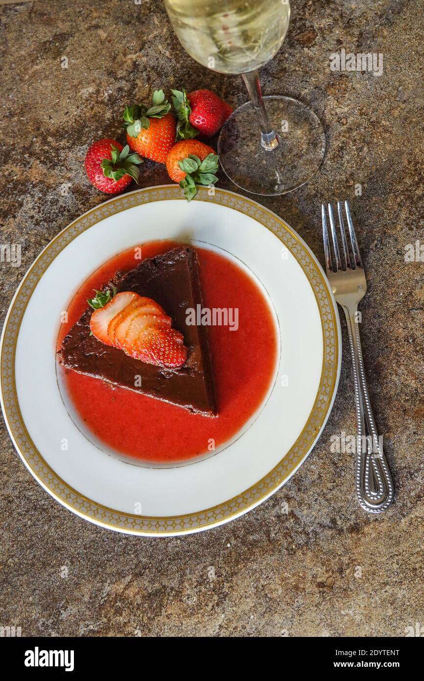 Terrina di cioccolato fatta in casa con una salsa di fragole fresca guarnita con una fragola fresca tagliata a fette Foto Stock