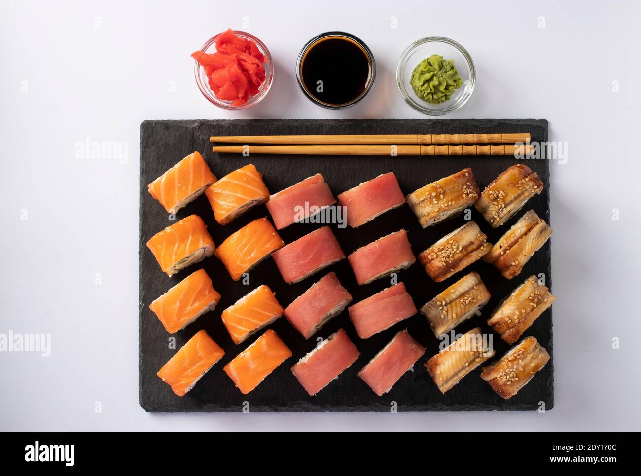 Cucina asiatica con sushi di salmone, tonno e anguilla con formaggio philadelphia su una tavola di ardesia su sfondo bianco. Vista dall'alto Foto Stock