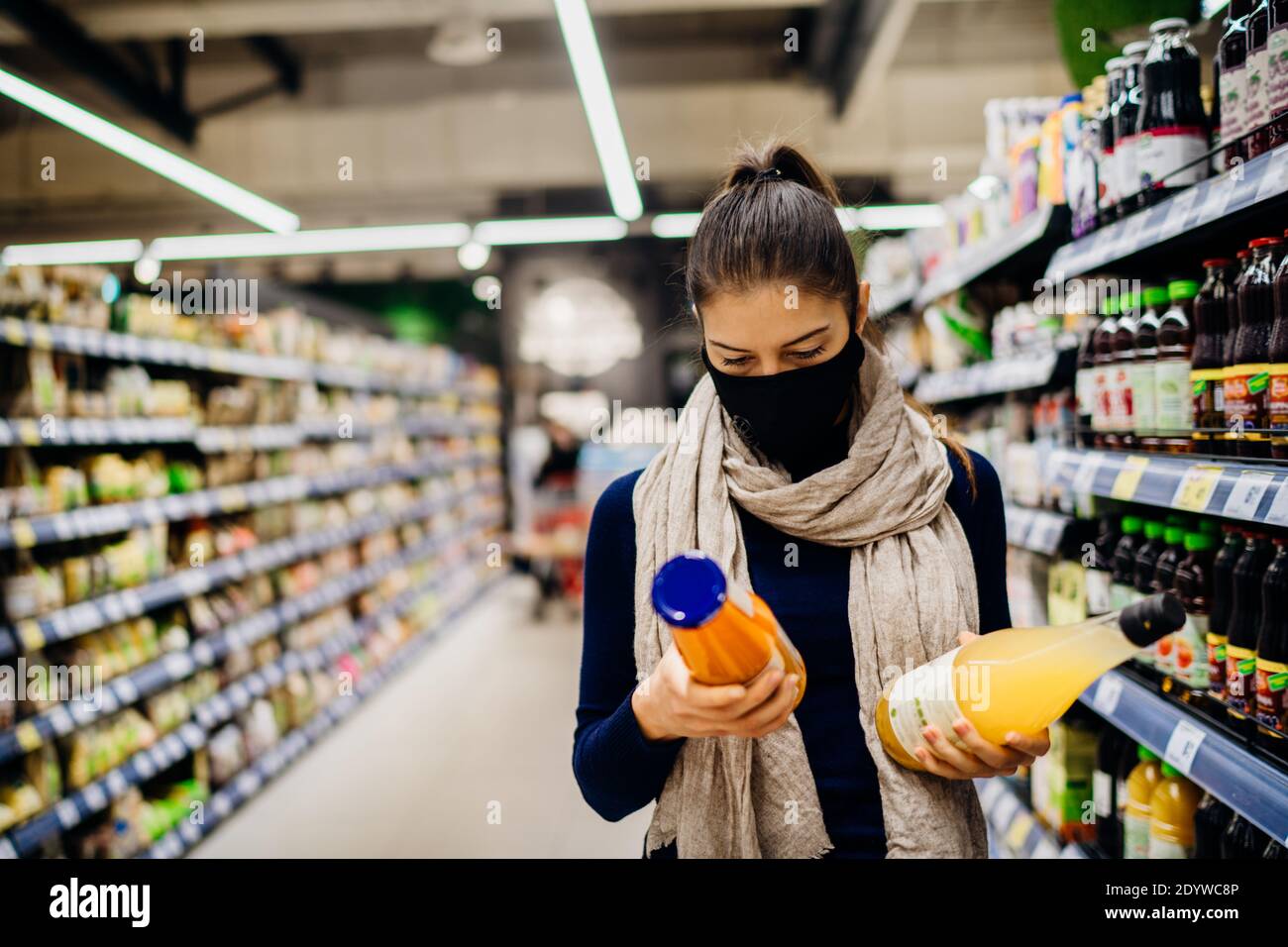 Giovane donna che indossa maschera protettiva shopping in un supermercato, acquisto Cibo biologico e succo naturale.mangiare cibo sano durante il coronavirus COVID - 19 Foto Stock
