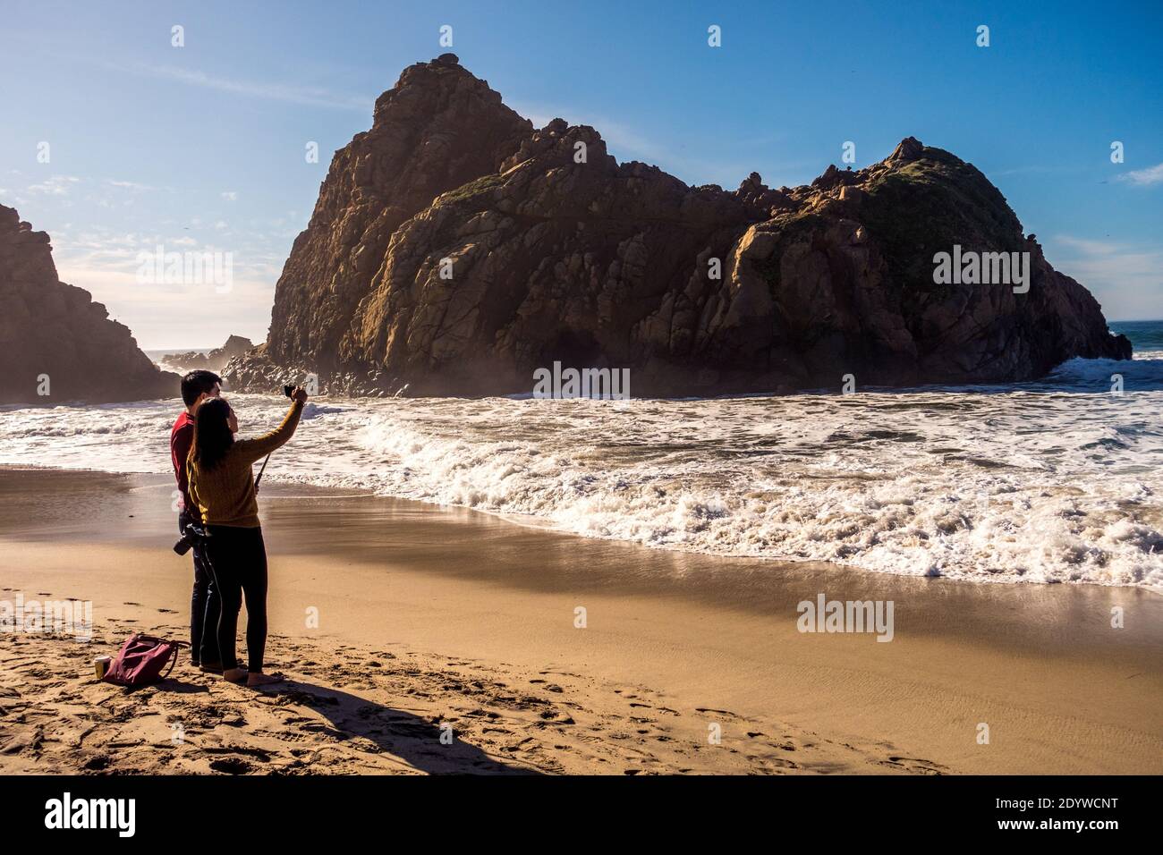 Coppia asiatica che prende un selfie di fronte all'iconica grotta marina a Pfeiffer Beach a Big sur, California, USA Foto Stock