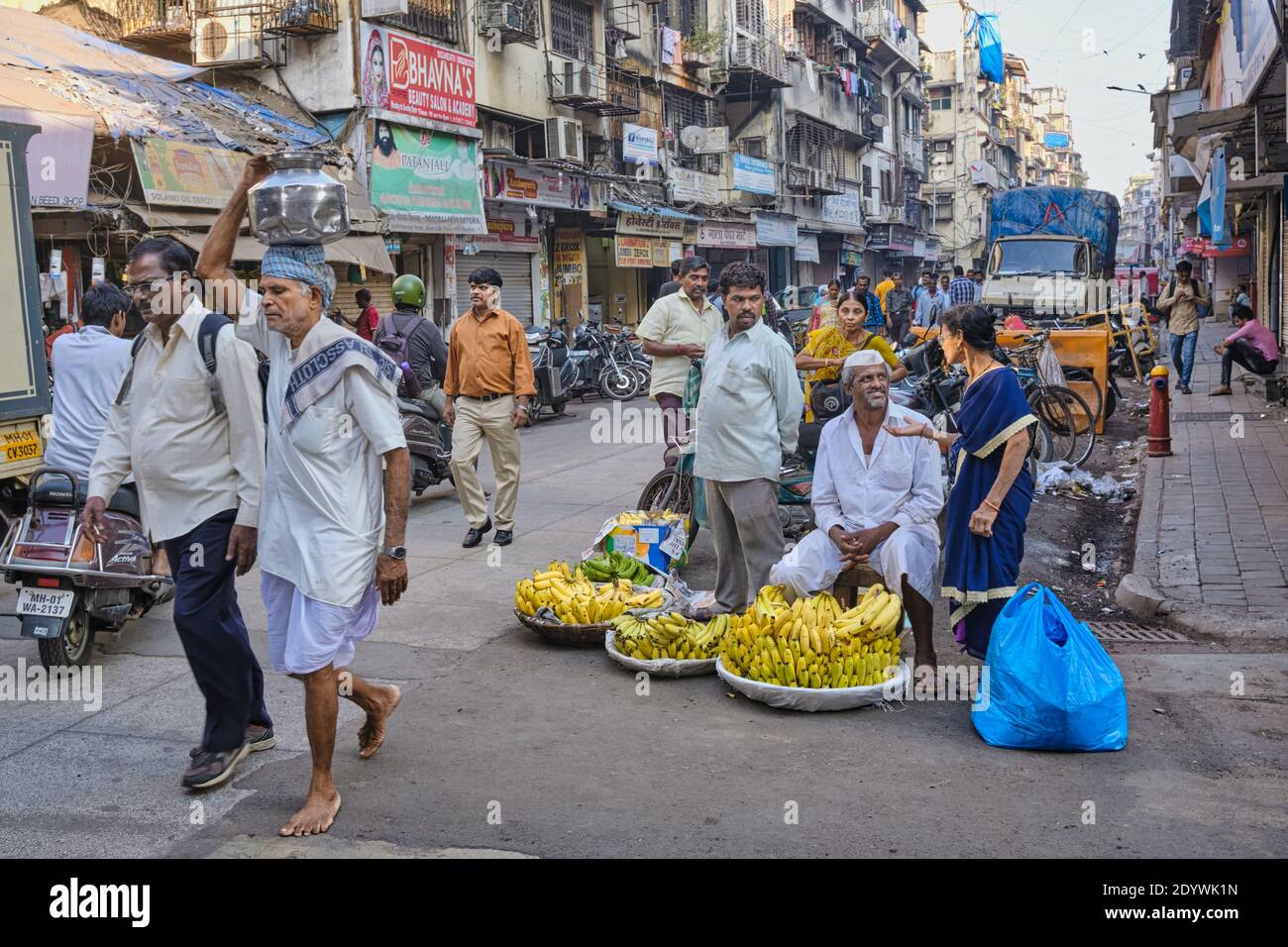 La trafficata Periman Nariman Street nella zona di Fort, Mumbai, India, piena di commercianti e acquirenti, un venditore di banane in primo piano Foto Stock