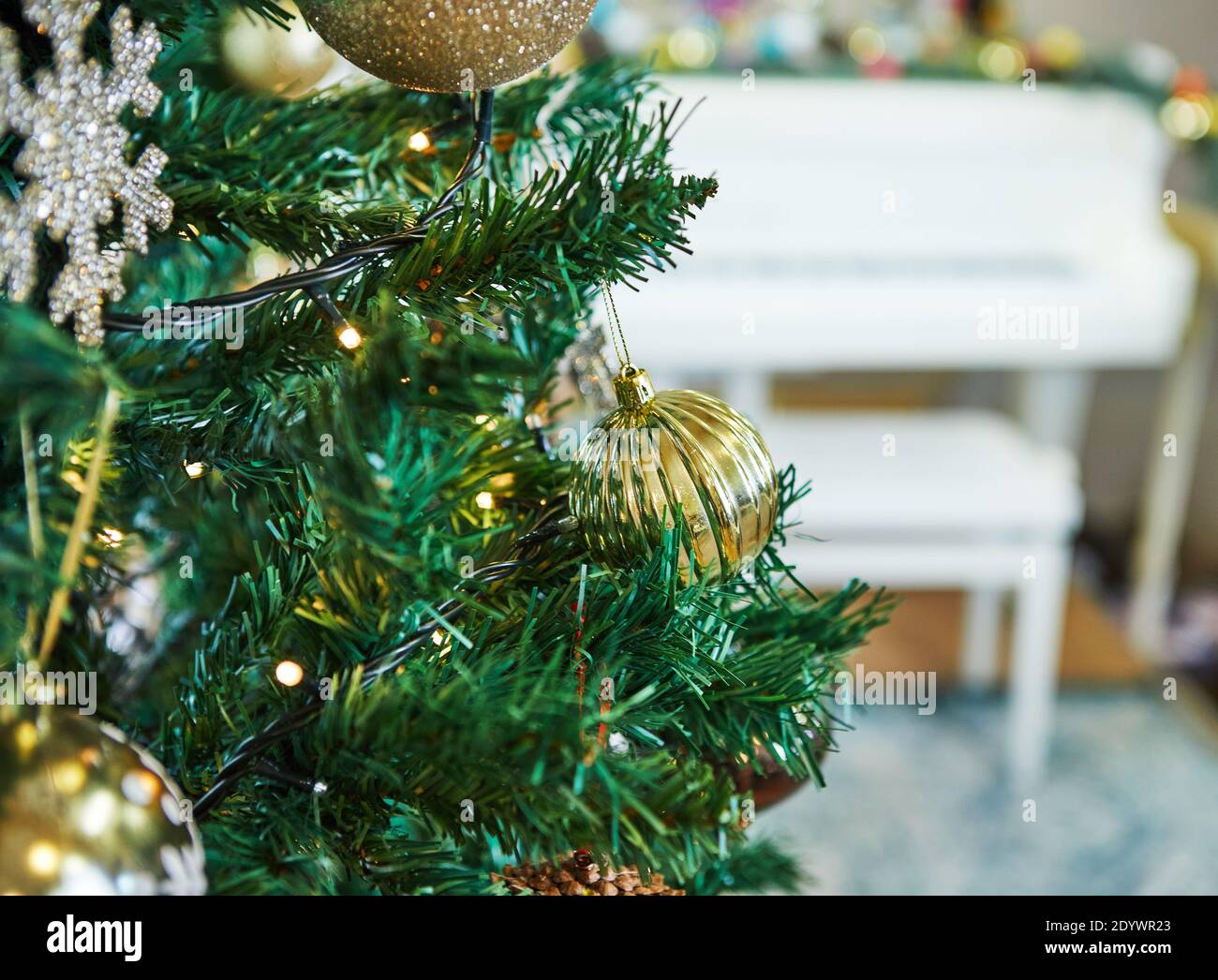Albero di Natale decorato con giocattoli. Sullo sfondo di un pianoforte bianco. Concetto di nuovo anno Foto Stock