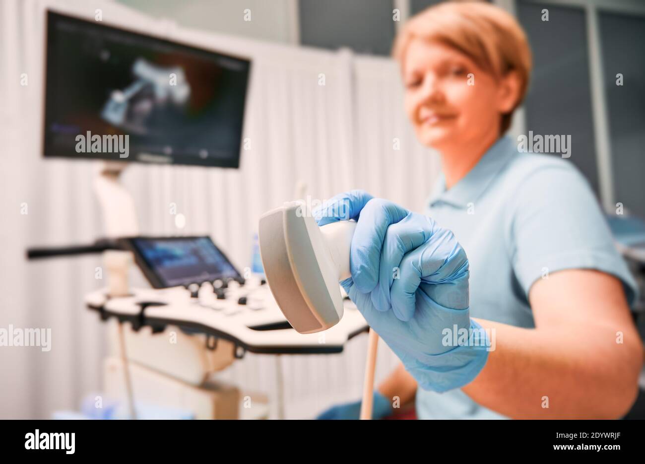 Concentrarsi sulle mani di un ecografo donna in guanti sterili che tengono il trasduttore a ultrasuoni. Medico femminile che utilizza un moderno scanner a ultrasuoni. Concetto di ultrasonografia, apparecchiature mediche, diagnostica a ultrasuoni Foto Stock