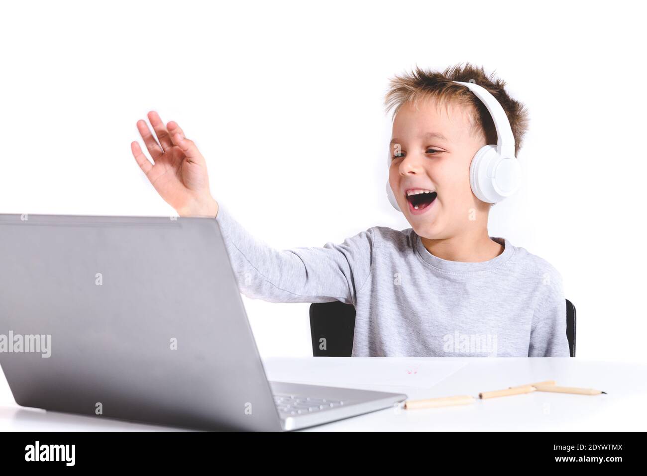 ritratto orizzontale di un ragazzo caucasico con cuffie bianche e mano ondulata davanti a un computer portatile. Concetto di videochiamata Foto Stock