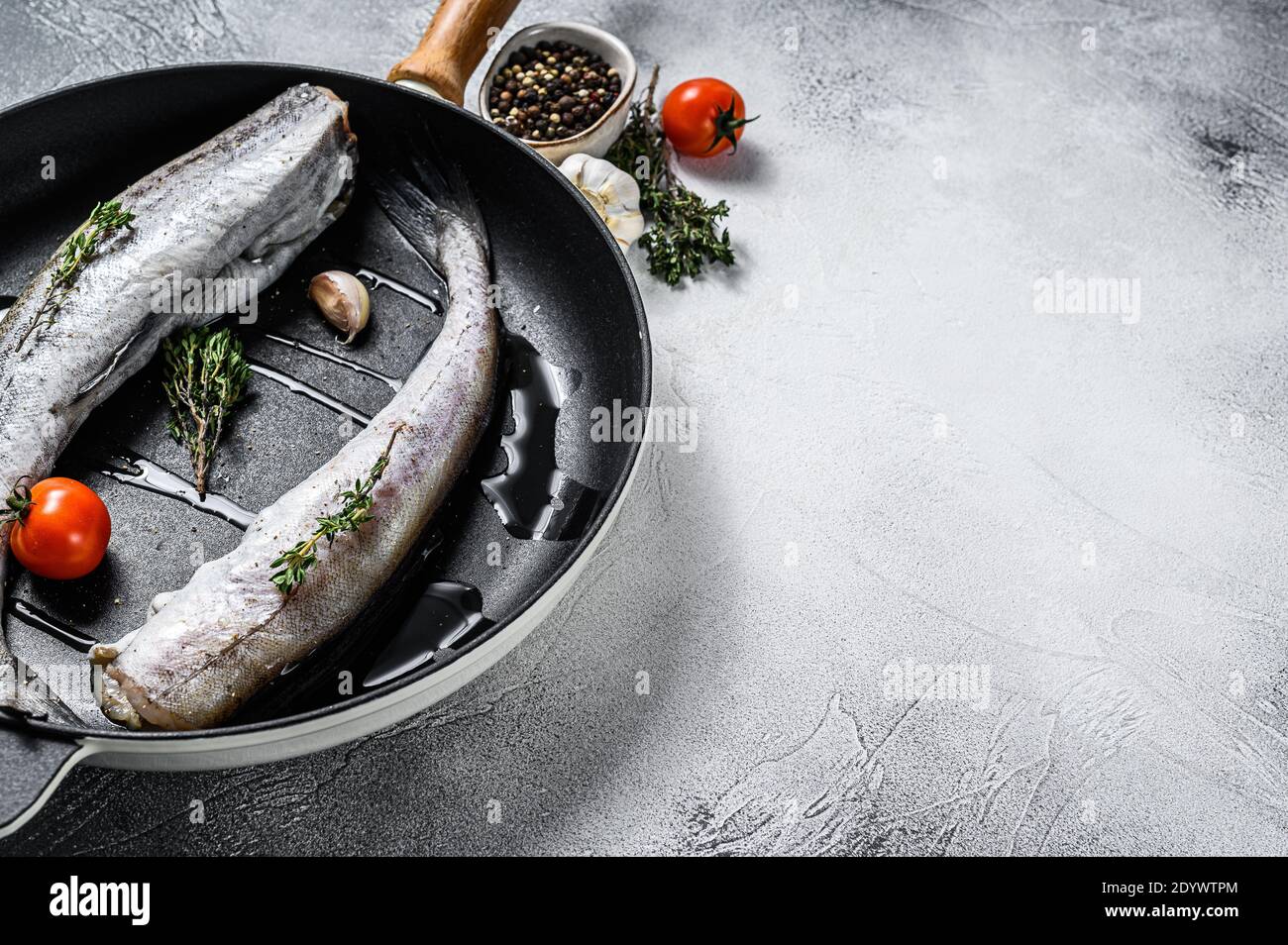 Pesce Pollock crudo in una padella. Frutti di mare biologici. Sfondo grigio. Vista dall'alto. Spazio di copia Foto Stock