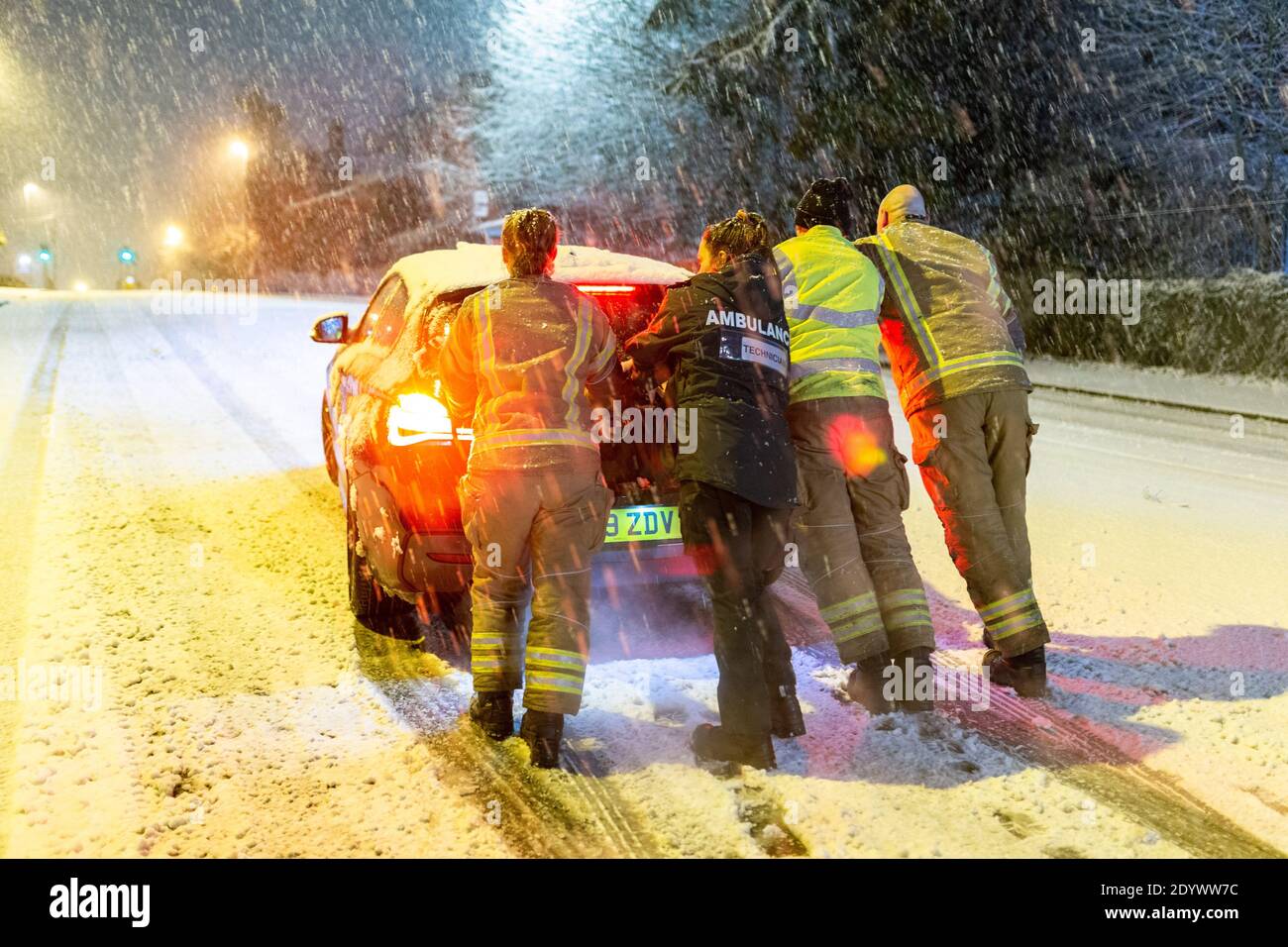 Cradley Heath, West Midlands, Regno Unito. 28 Dic 2020. Una squadra di fuoco spinge l'auto di un paramedico incagliato su una collina innevata questa mattina, mentre cerca di farla funzionare per il turno della sua giornata. La neve si deposita e causa i ritardi di traffico in Cradley Heath nelle West Midlands Credit: Peter Lopeman/Alamy Live News Foto Stock