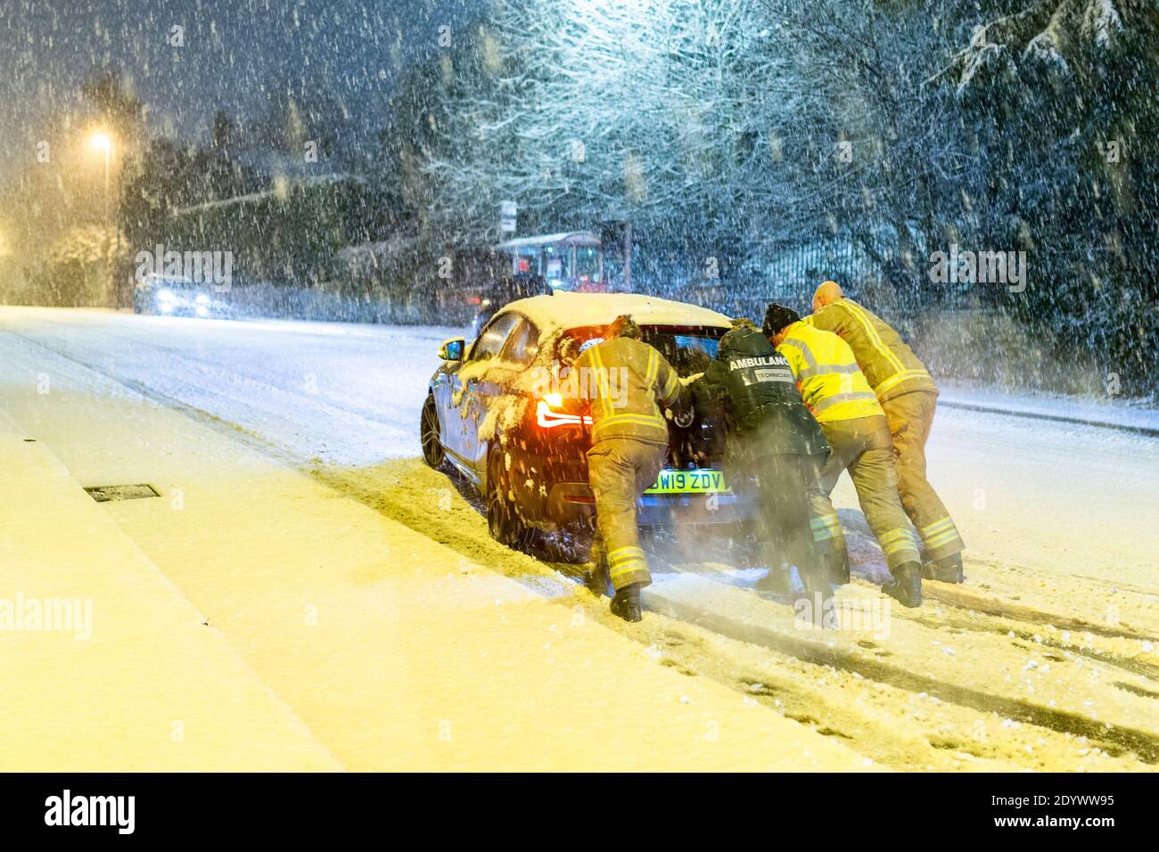 Cradley Heath, West Midlands, Regno Unito. 28 Dic 2020. Una squadra di fuoco spinge l'auto di un paramedico incagliato su una collina innevata questa mattina, mentre cerca di farla funzionare per il turno della sua giornata. La neve si deposita e causa i ritardi di traffico in Cradley Heath nelle West Midlands Credit: Peter Lopeman/Alamy Live News Foto Stock