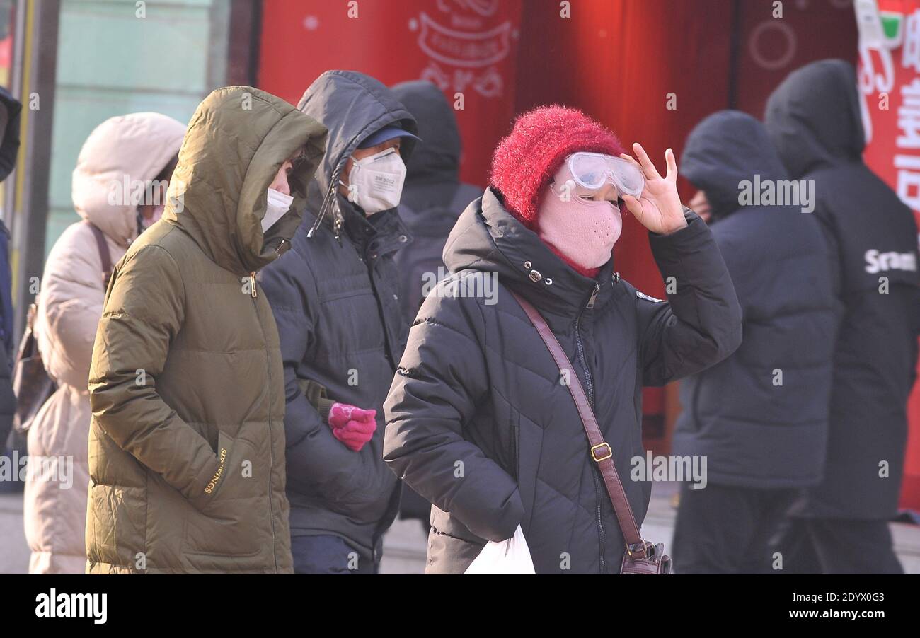 I cittadini camminano in strada con cappotto pesante e cappello mentre l'onda fredda attacca la città e la temperatura scende di circa 10 gradi Celsius, Harbin cit Foto Stock