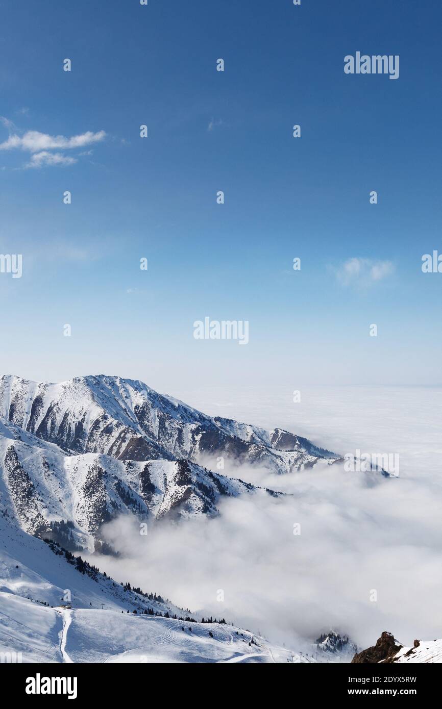 Stazione sciistica di Cloudy Tian Shan cime montagna nella nebbia vicino Almaty città. Scatto verticale. Foto Stock