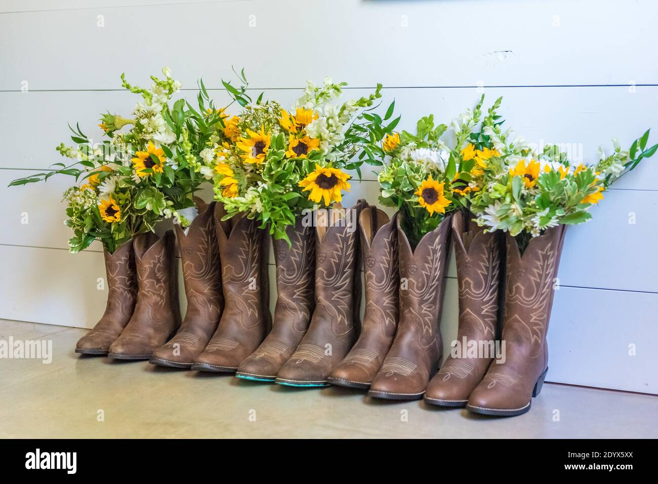 Fila di stivali da cowboy marroni con bouquet di fiori per una cerimonia nuziale Foto Stock